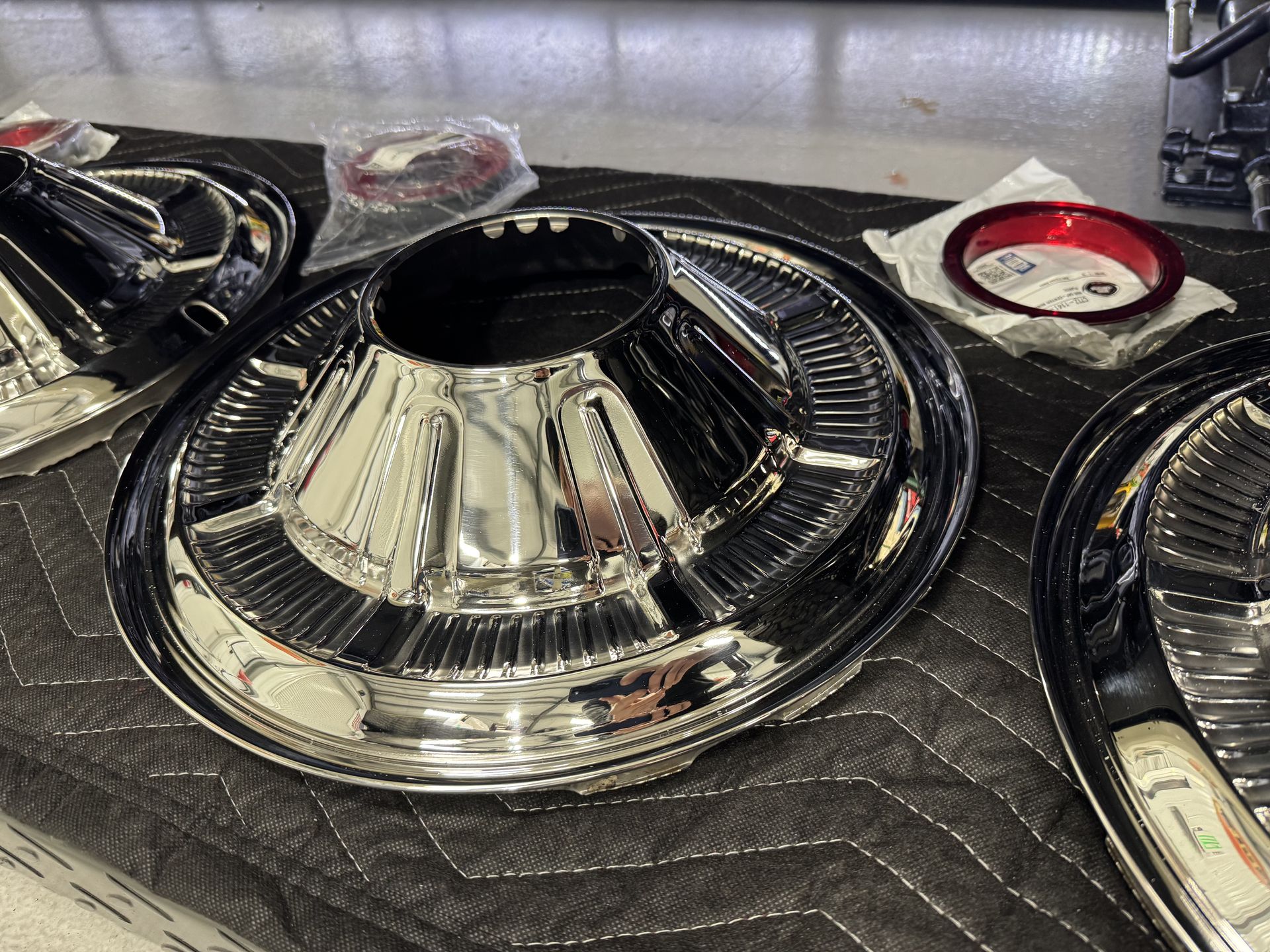 A close up of a chrome wheel cover on a quilted surface