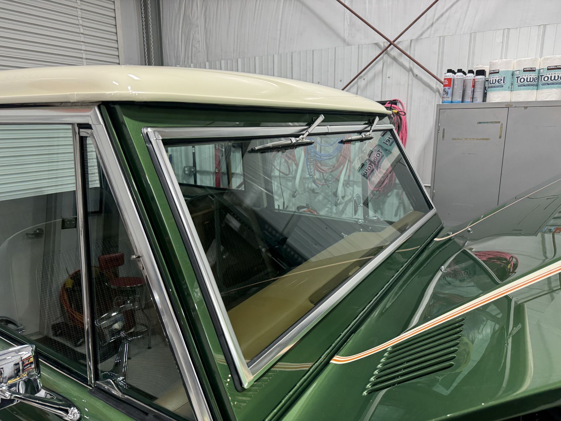 A green car with a white roof is parked in a garage.