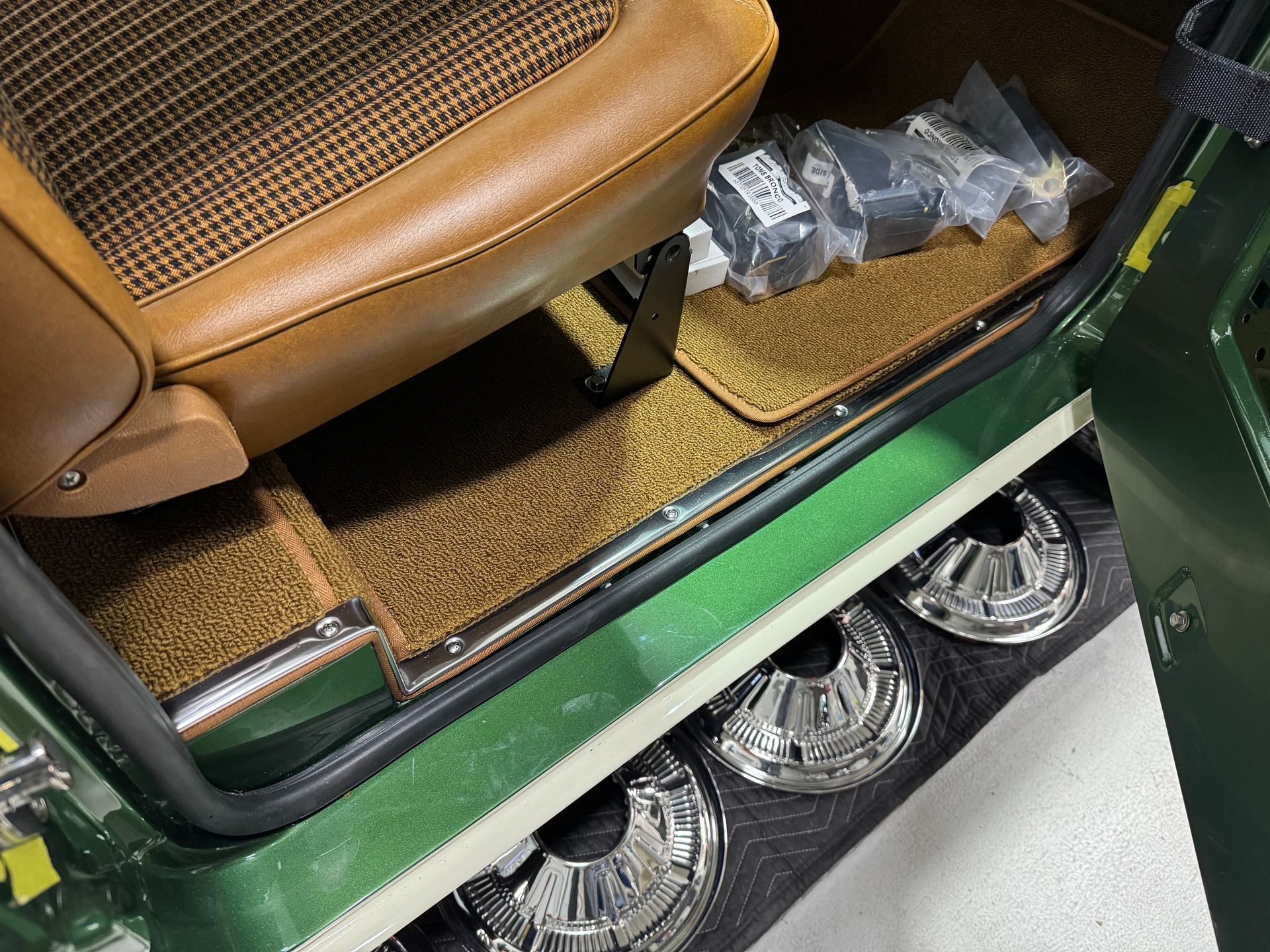 A green car with a brown seat and a brown door mat.