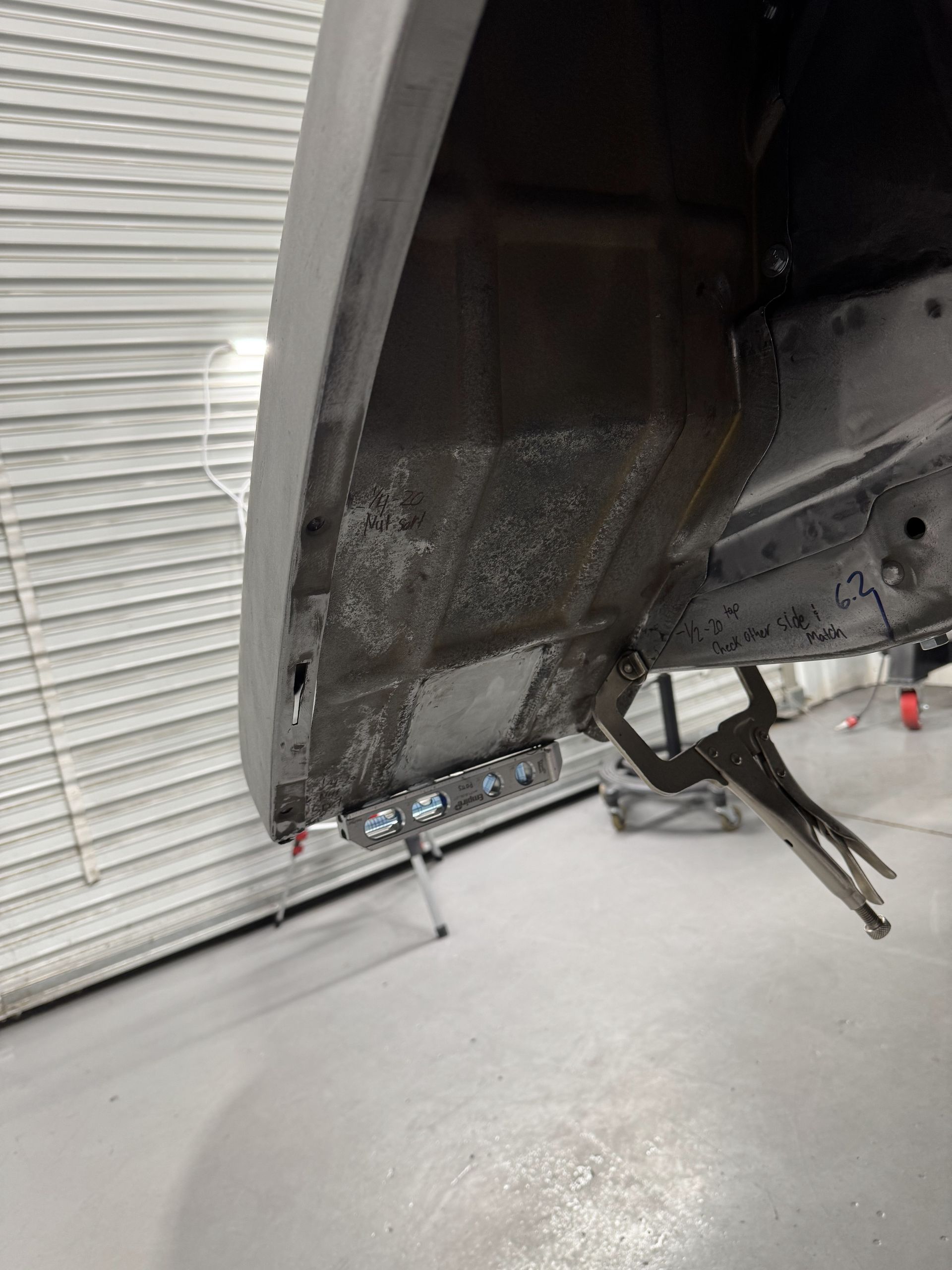 A car is being worked on in a garage with a pair of pliers.