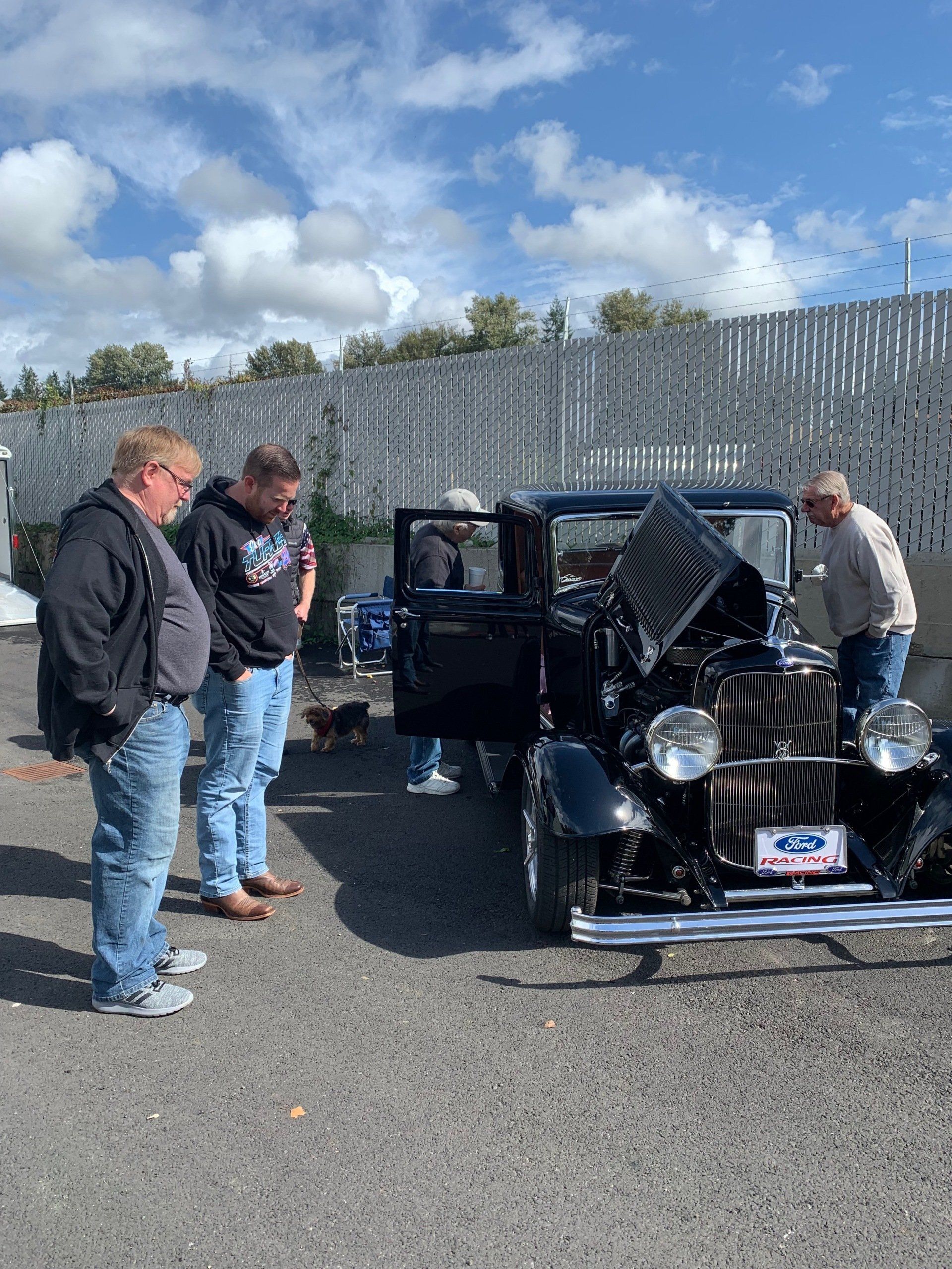 A group of men are standing next to an old black car.