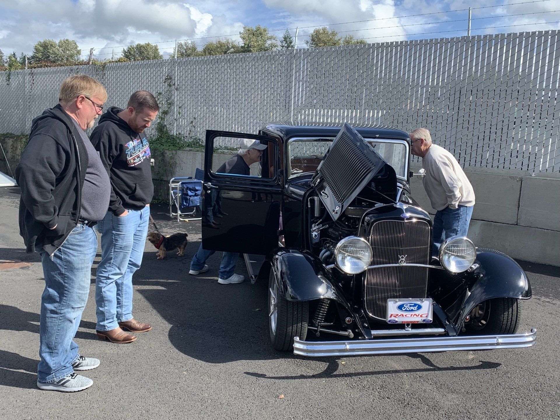 A group of men are looking at an old black car.