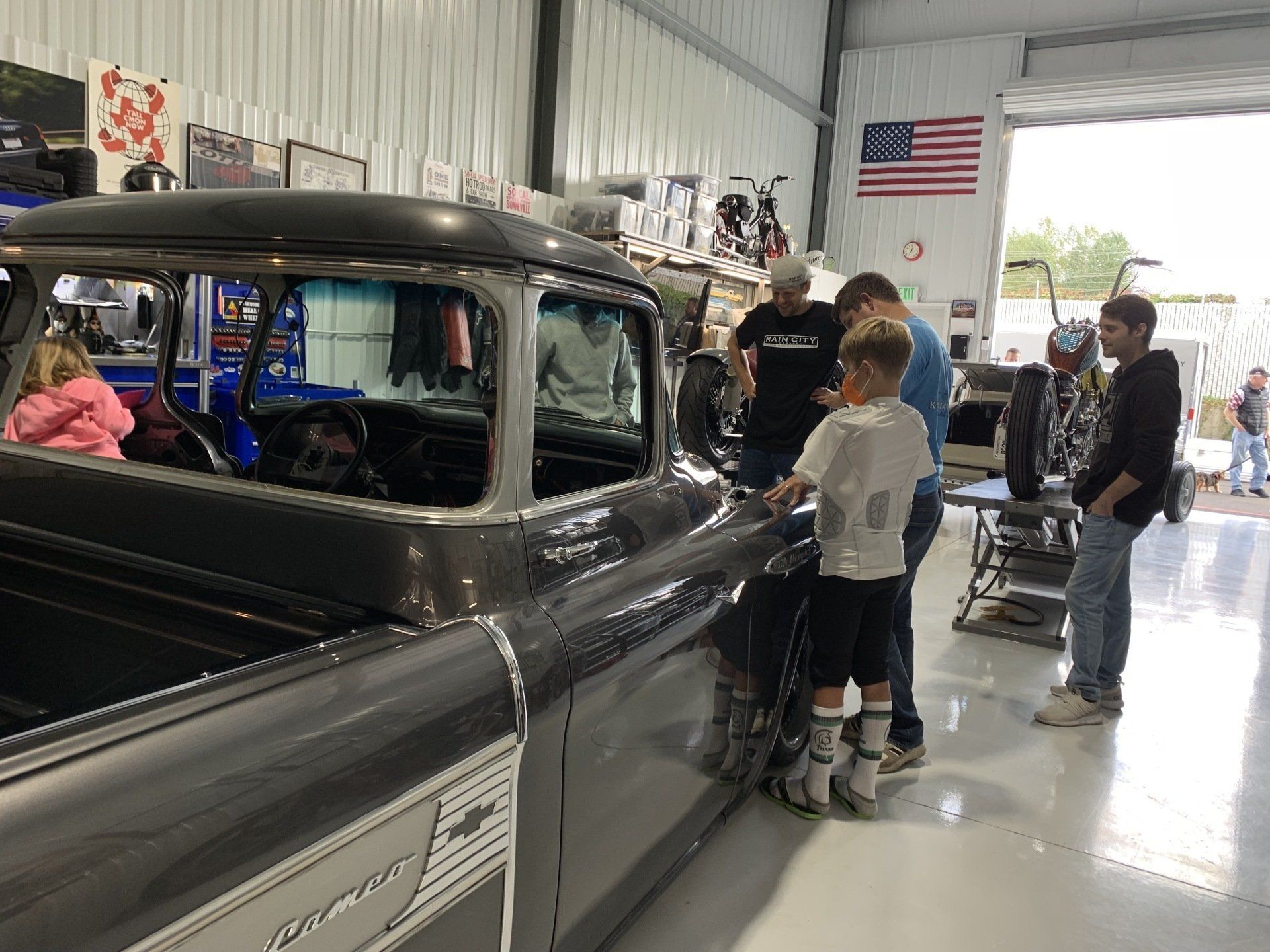 A group of people are looking at a truck in a garage.