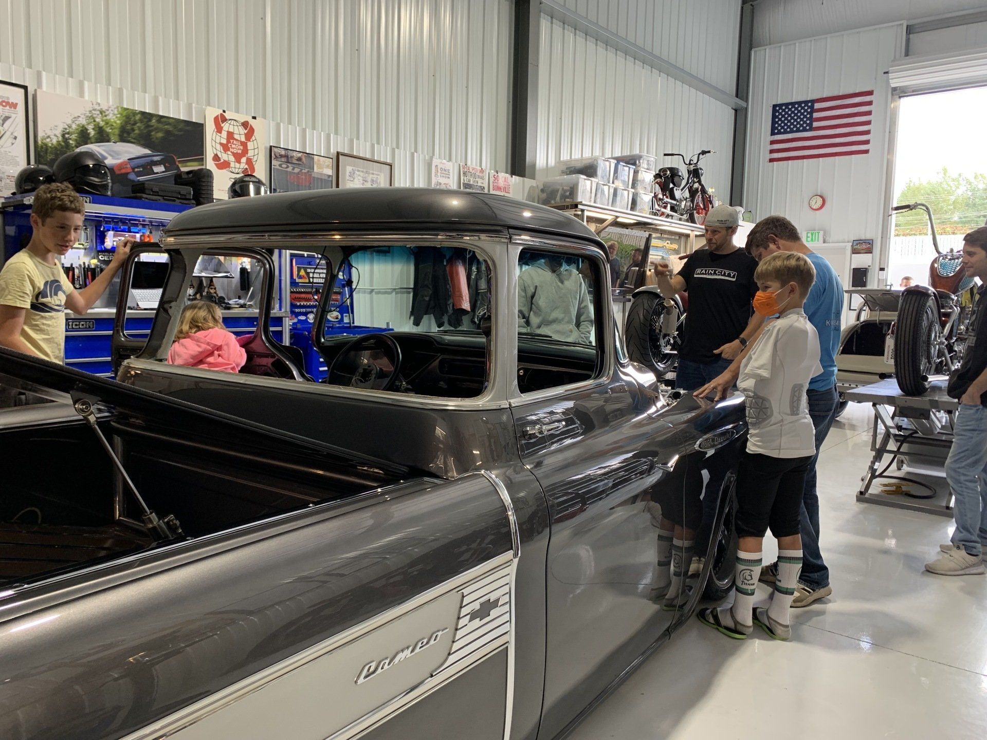 A group of people are standing around a truck in a garage.