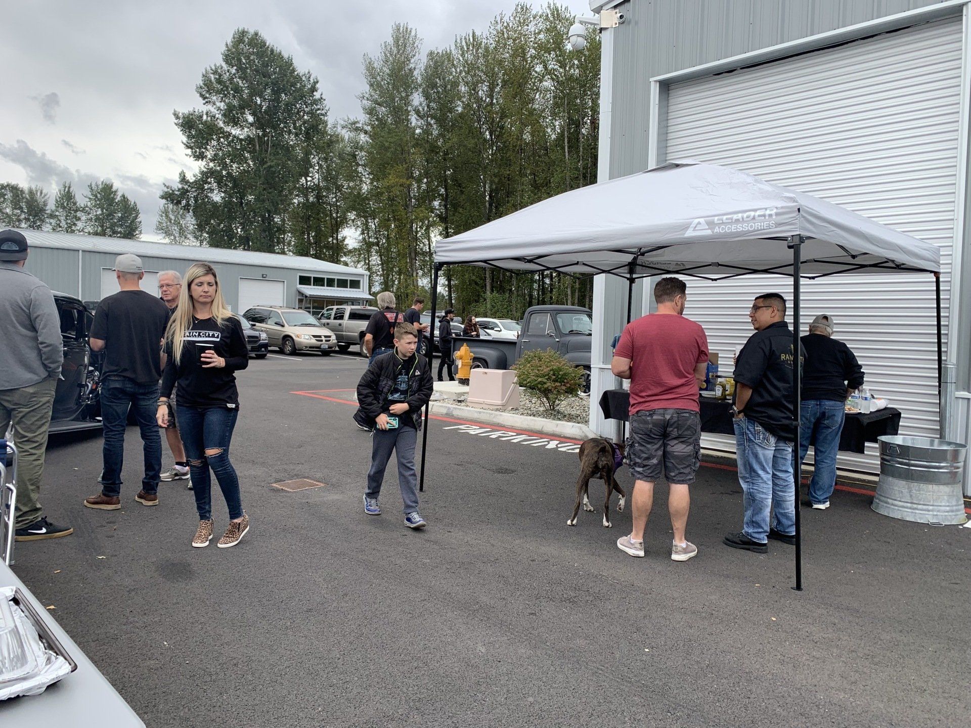 A group of people are standing under a canopy in a parking lot.