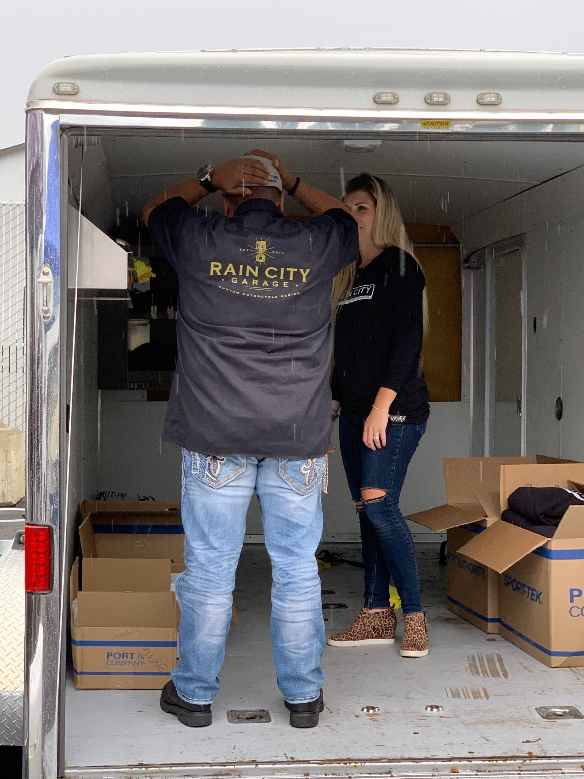 A man and a woman are standing in the back of a trailer.