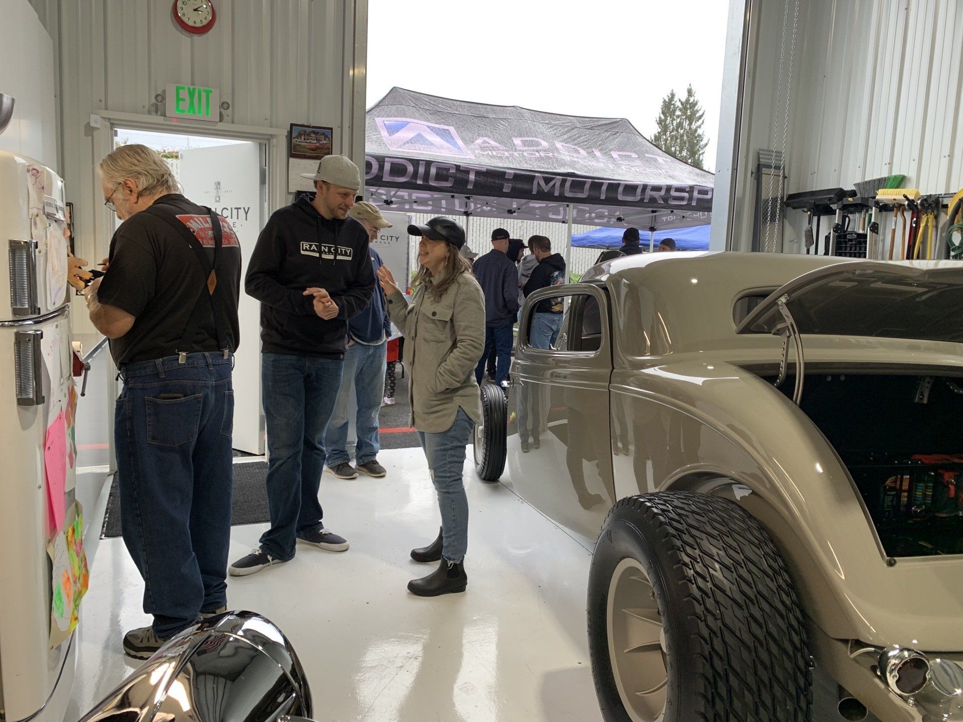 A group of people are standing around a car in a garage.
