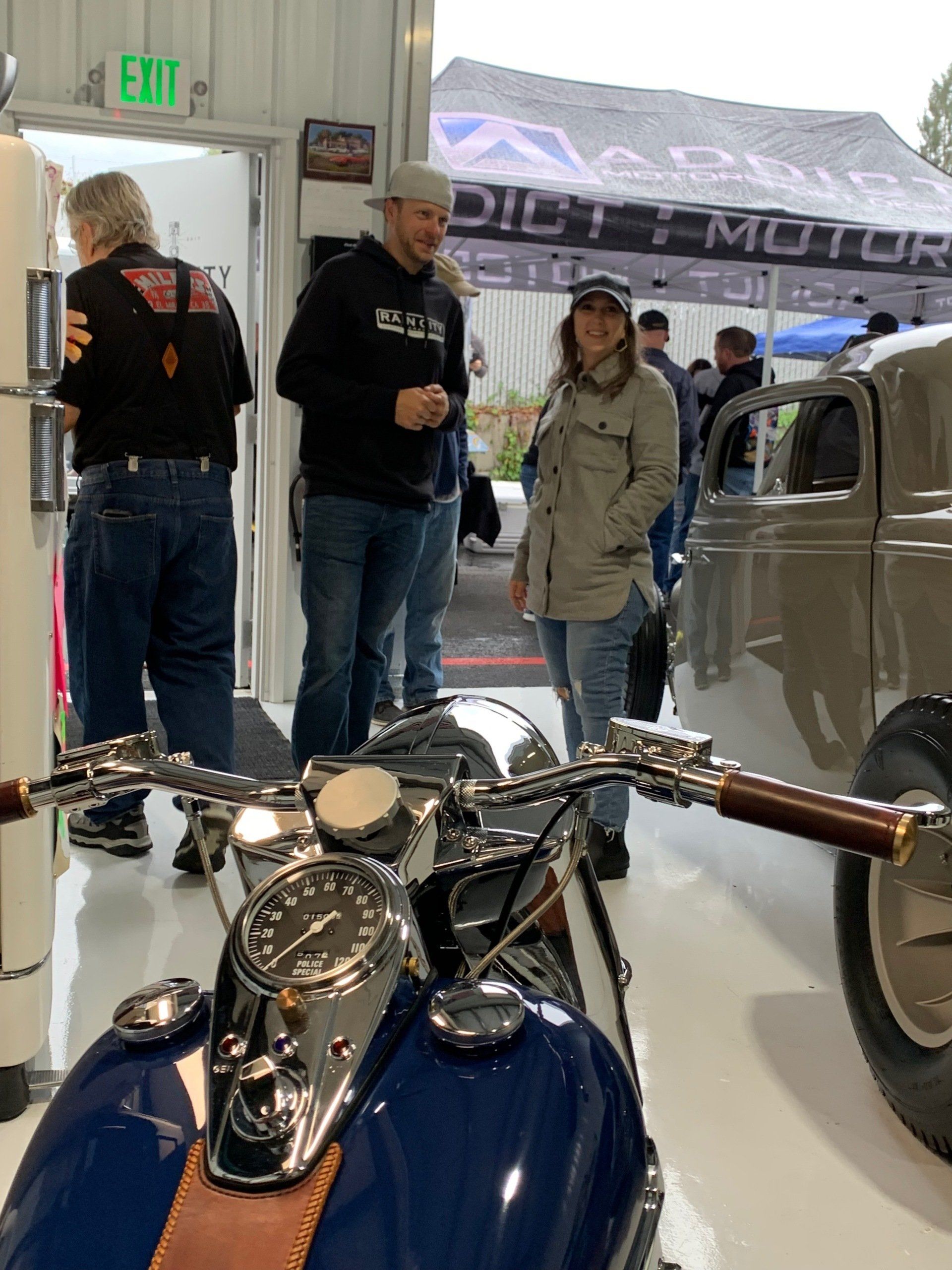 A group of people are standing around a motorcycle in a garage.