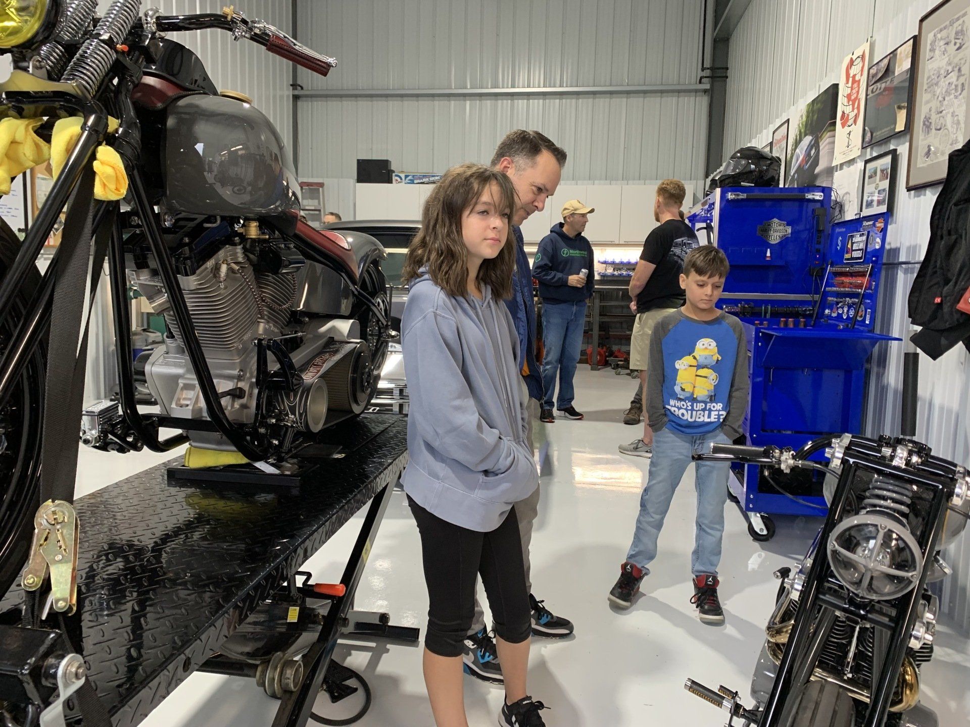 A group of people are looking at a motorcycle in a garage.