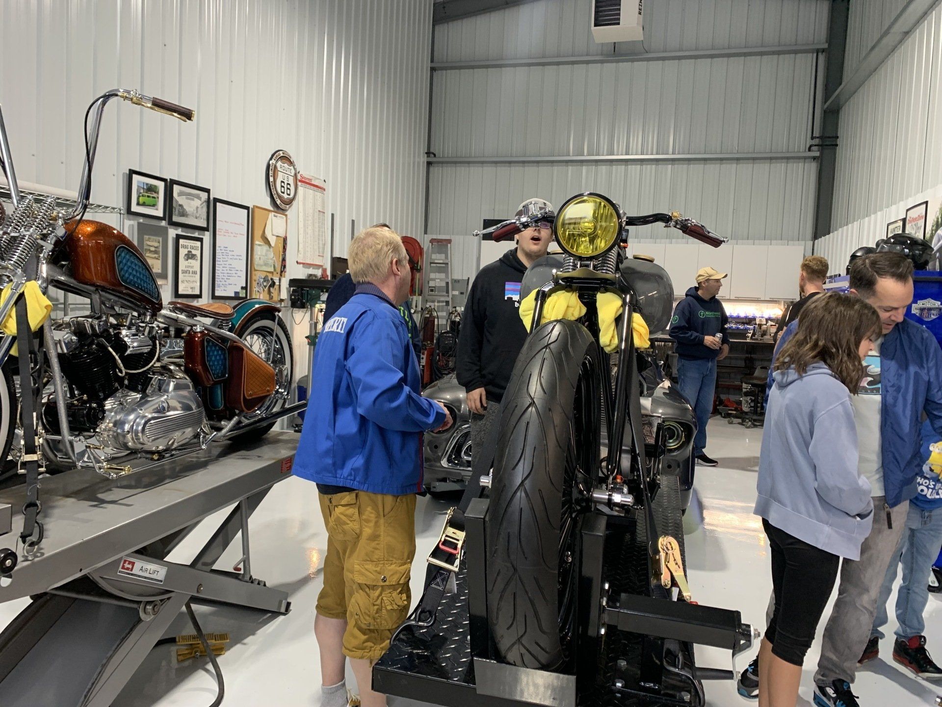 A group of people are standing around a motorcycle in a garage.