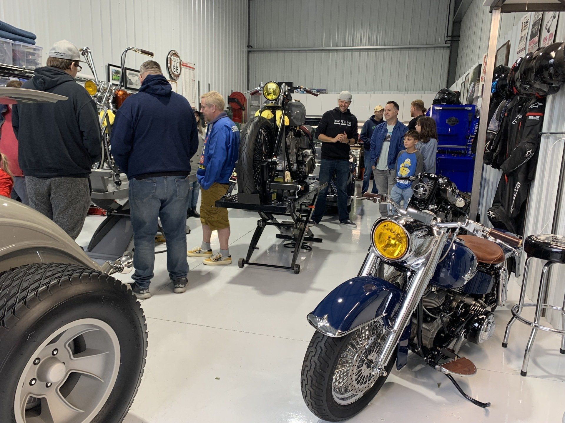 A group of people are standing around a motorcycle in a garage.
