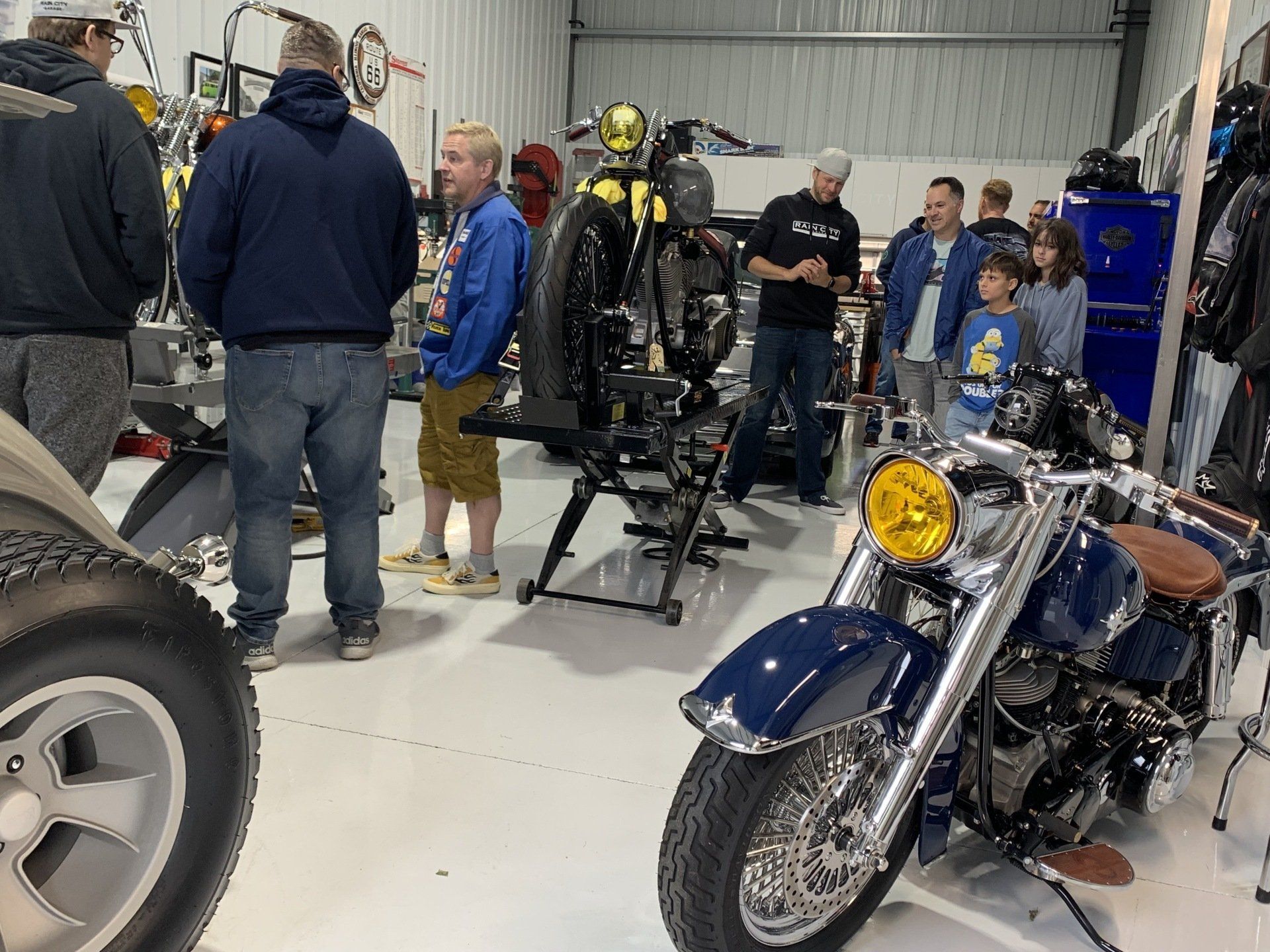 A group of people are standing around a motorcycle in a garage.