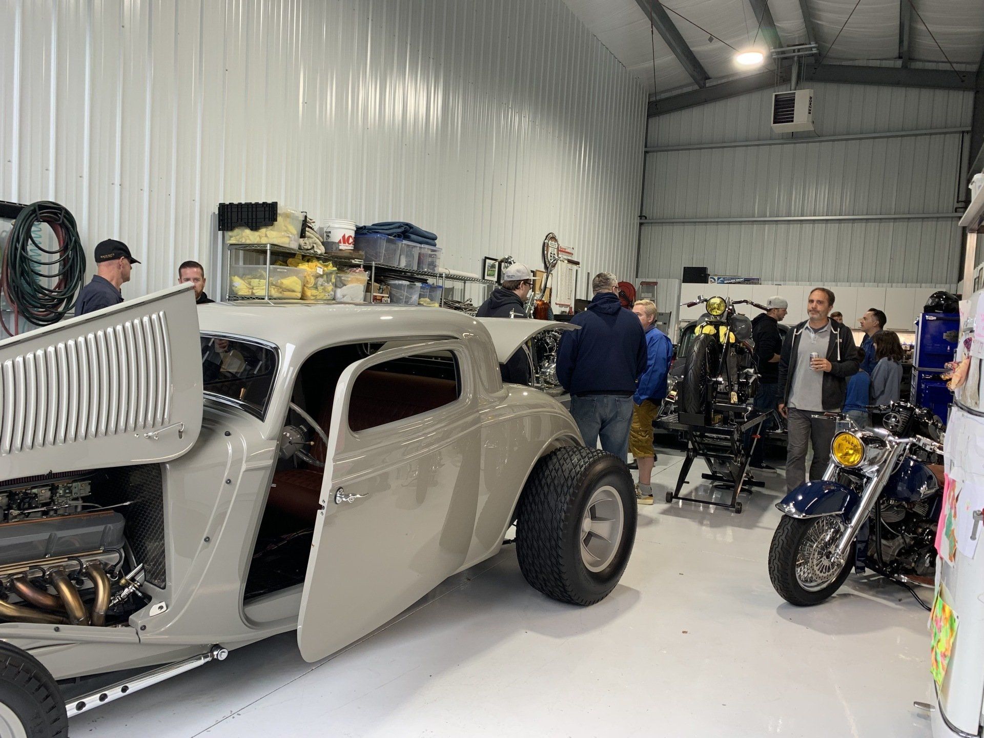 A group of people are standing around a car in a garage.