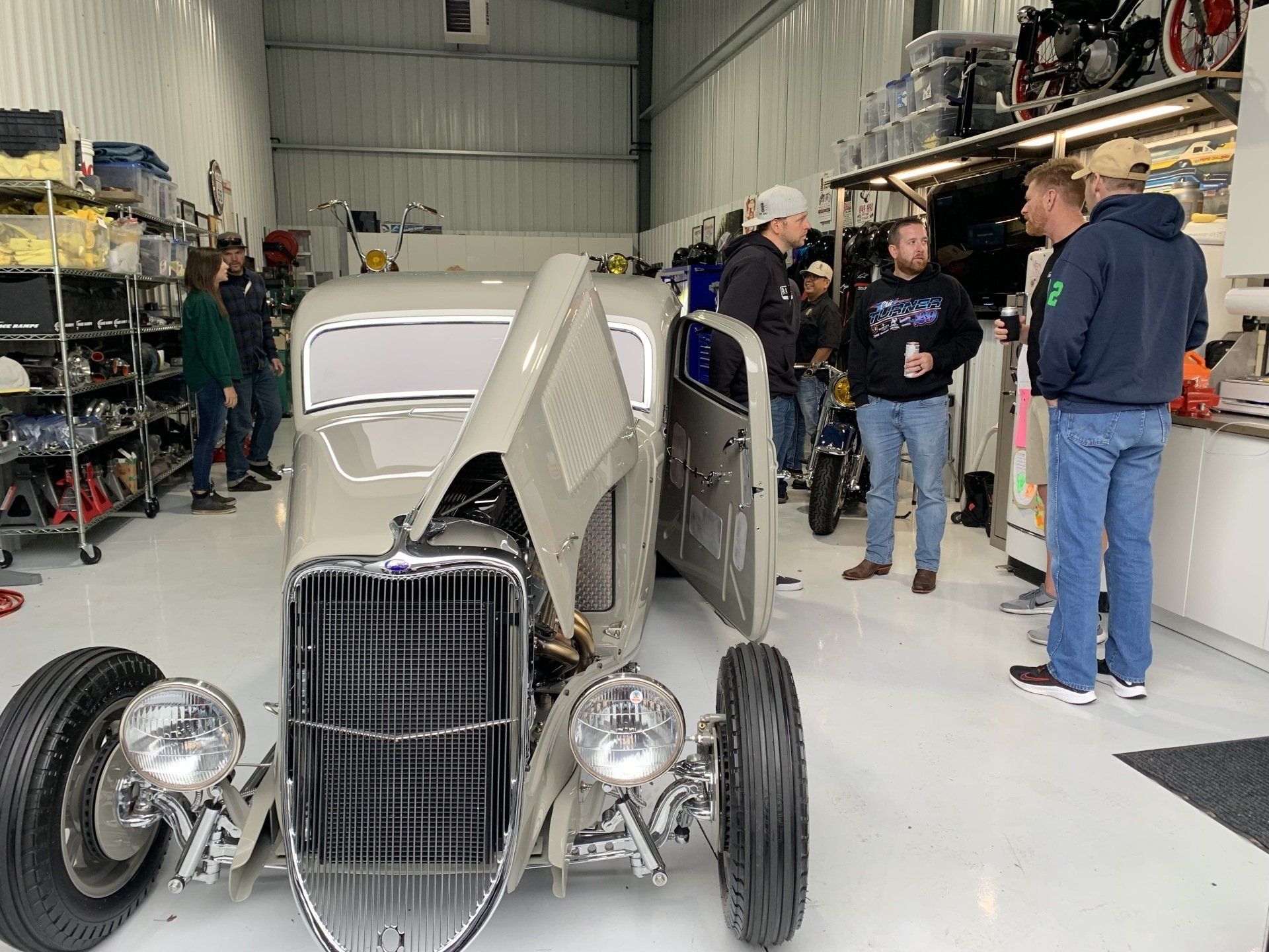 A group of men are standing around a car in a garage.