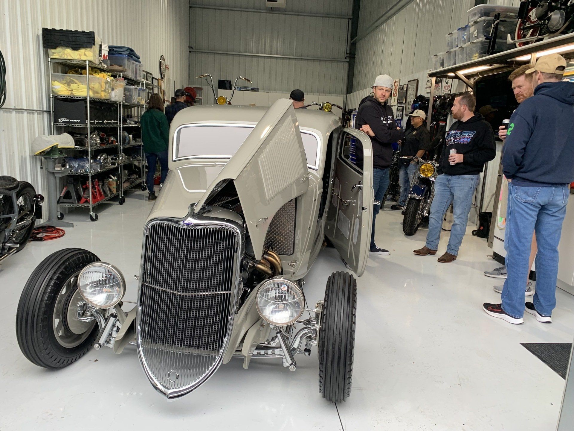 A group of men are standing around a car in a garage.