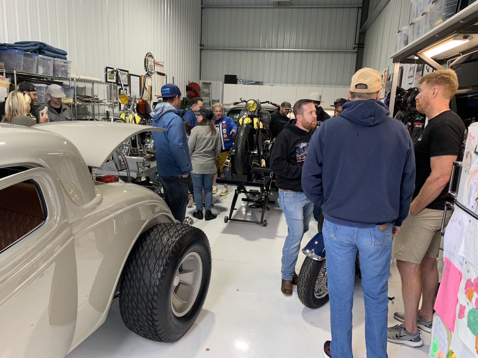 A group of people are standing around a car in a garage.