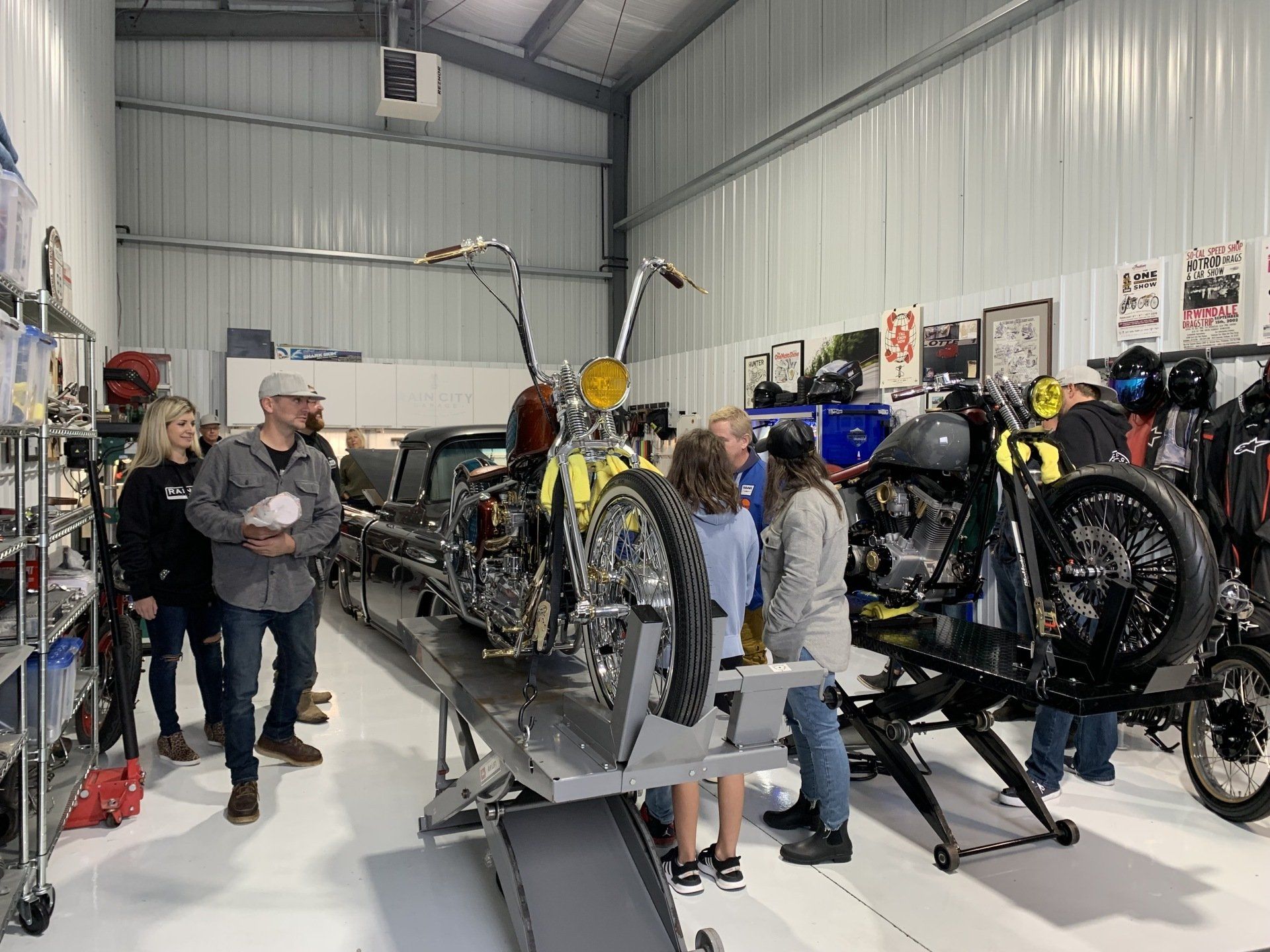 A group of people are standing around a motorcycle in a garage.