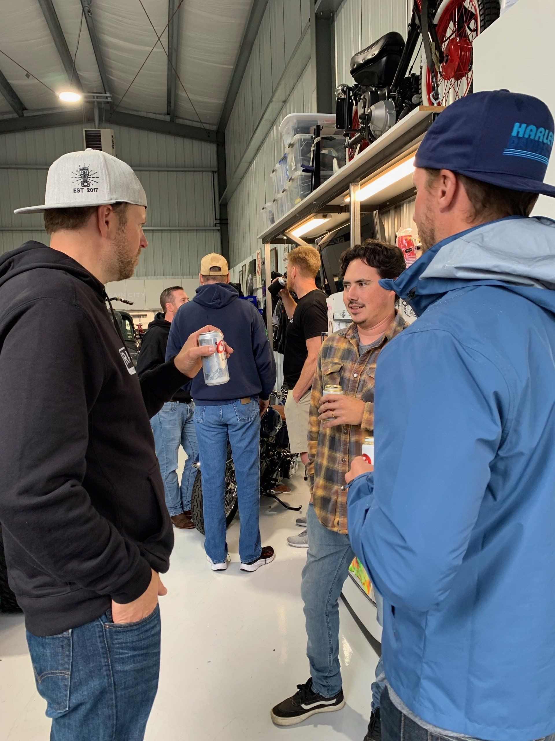 A group of men are standing in a room talking to each other.