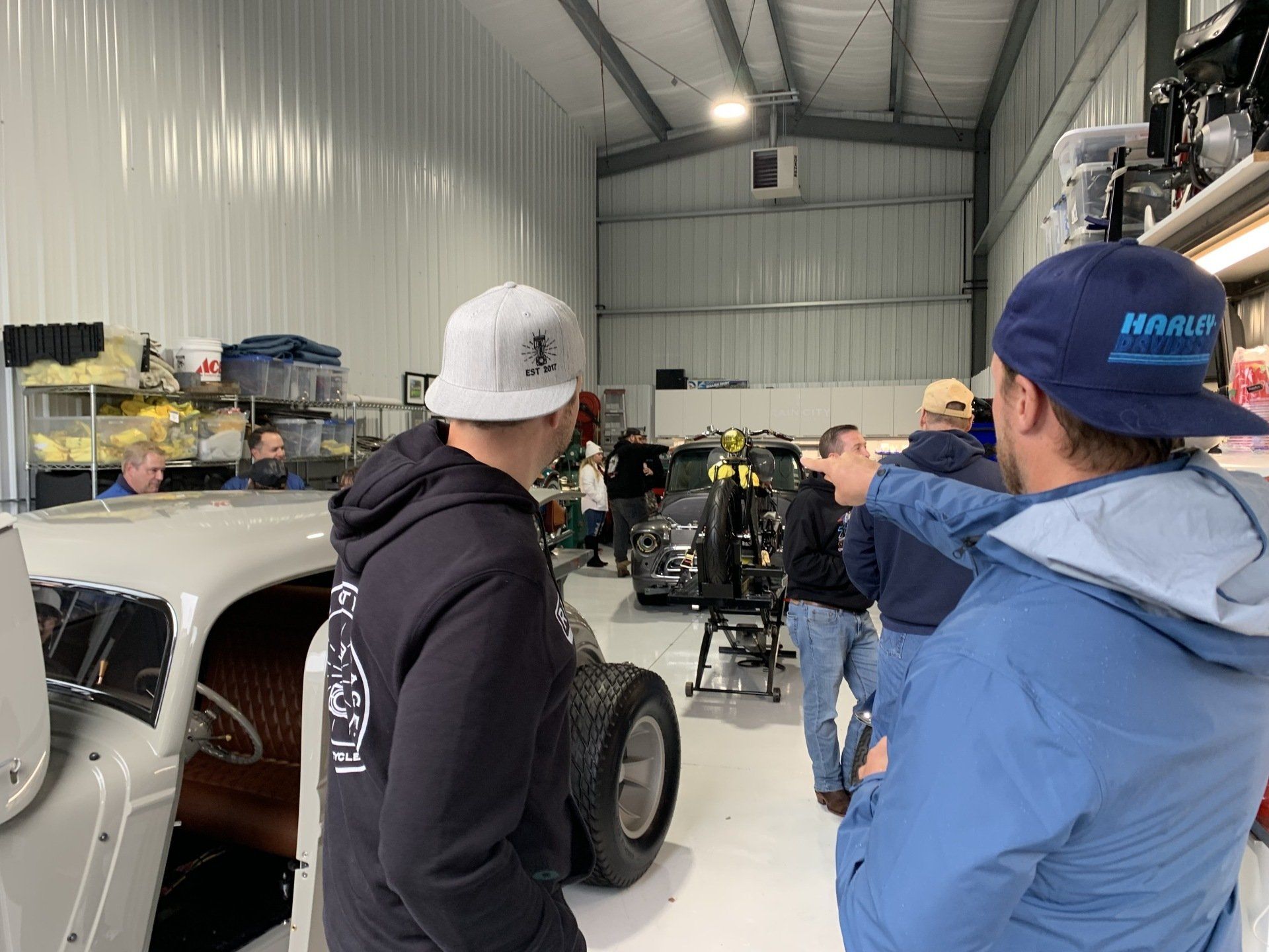 A group of men are standing in a garage looking at a car.