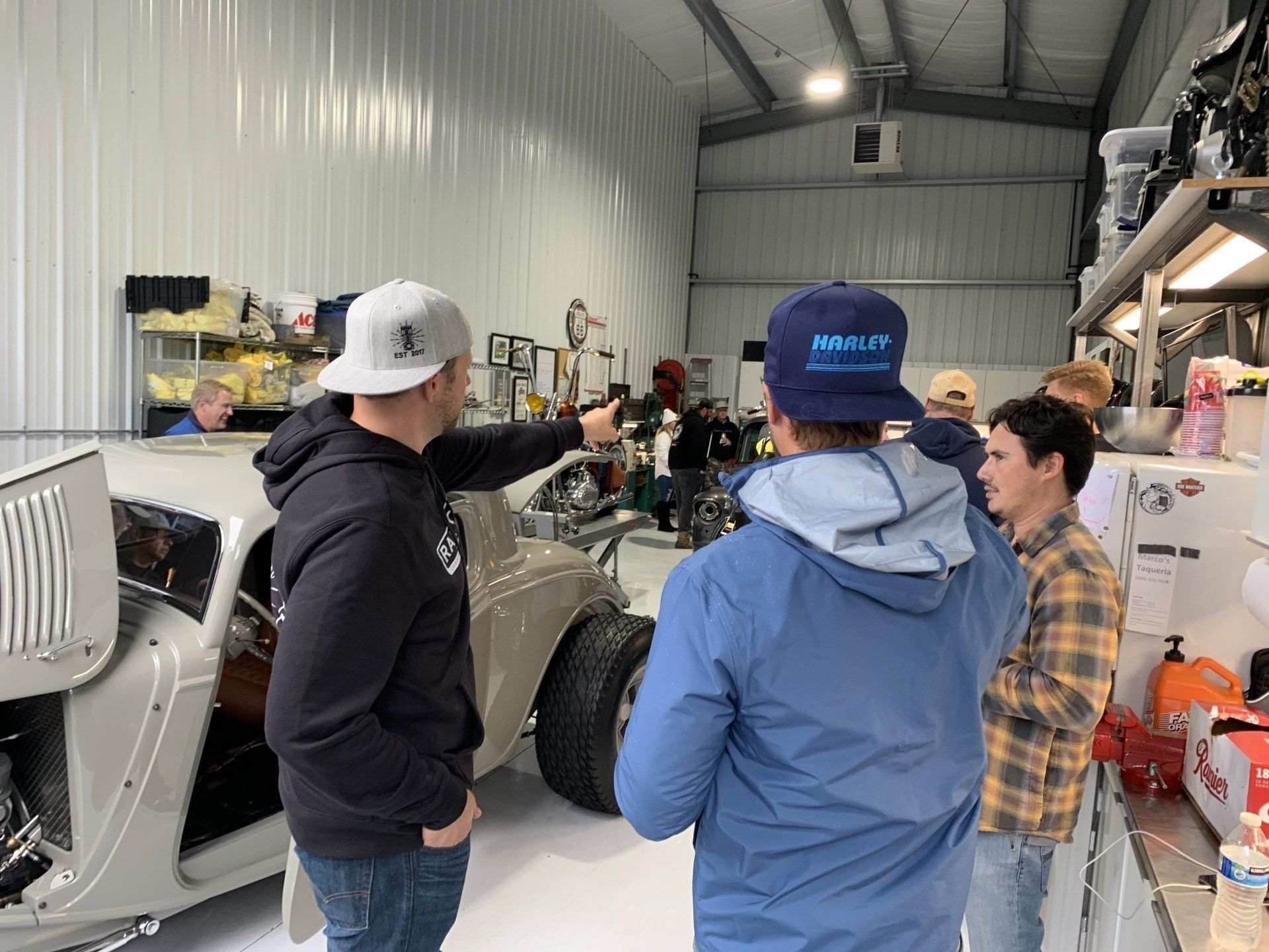 A group of men are standing around a car in a garage.