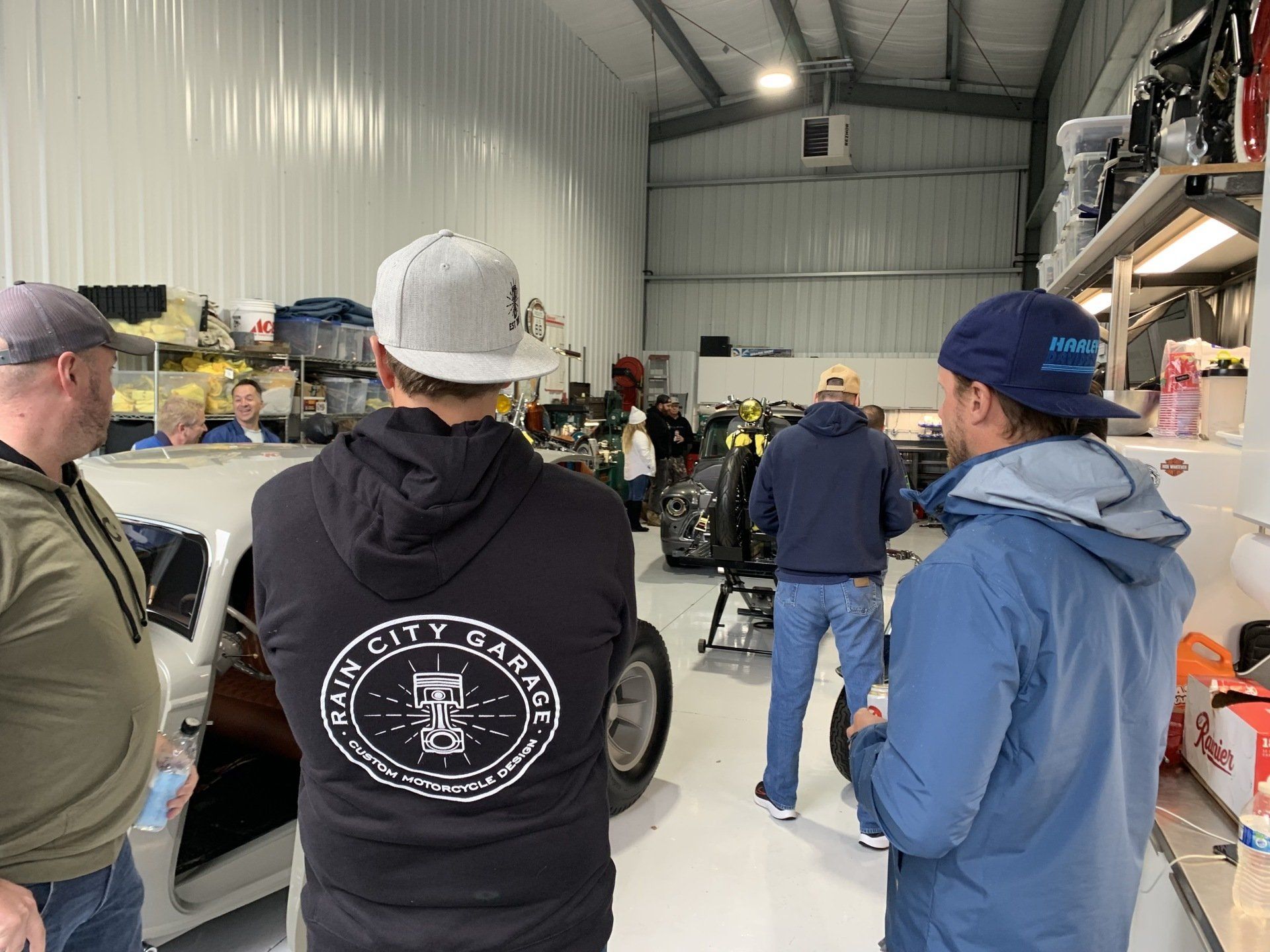 A group of men are standing in a garage looking at a car.