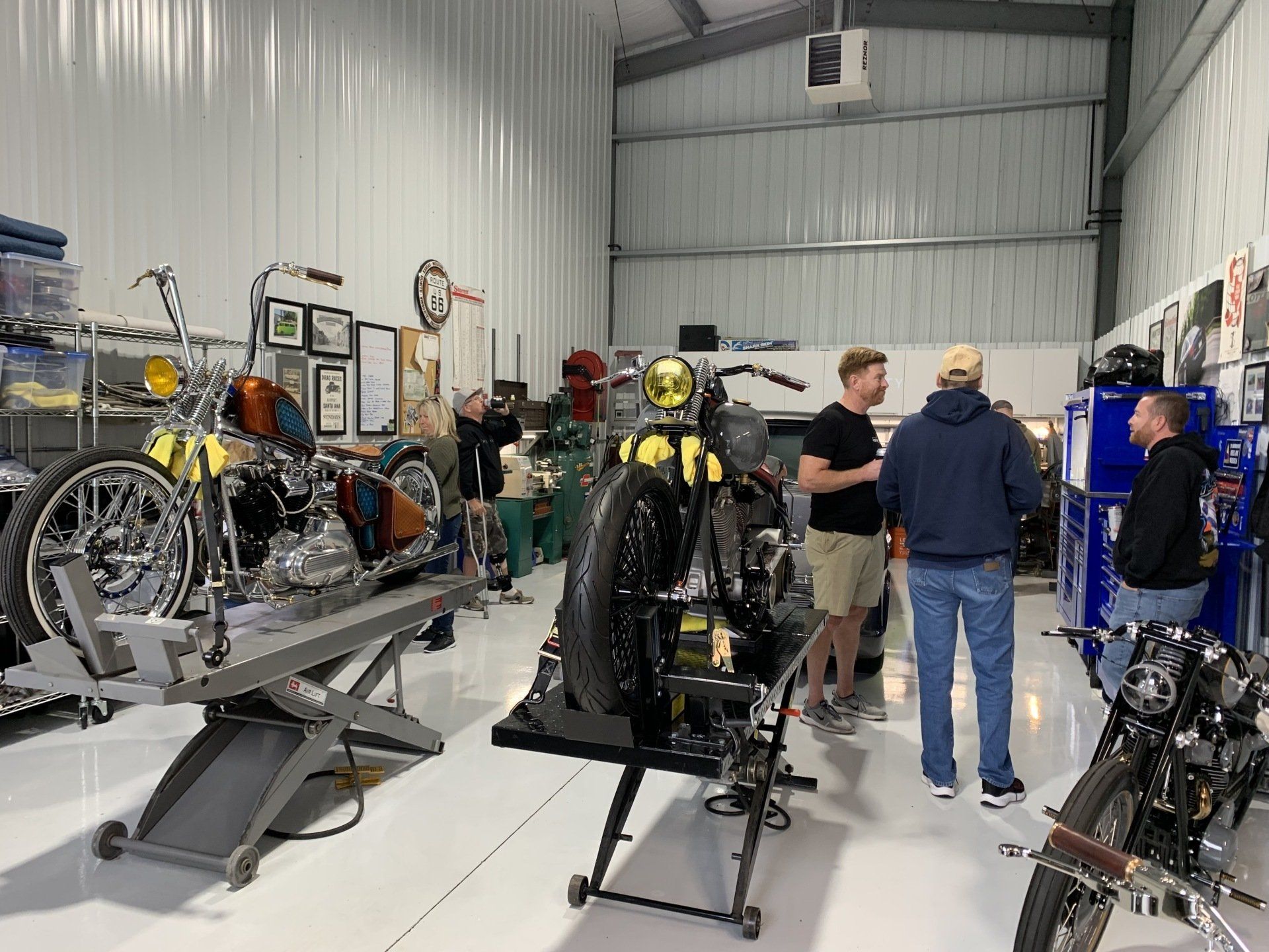 A group of men are standing around a motorcycle in a garage.