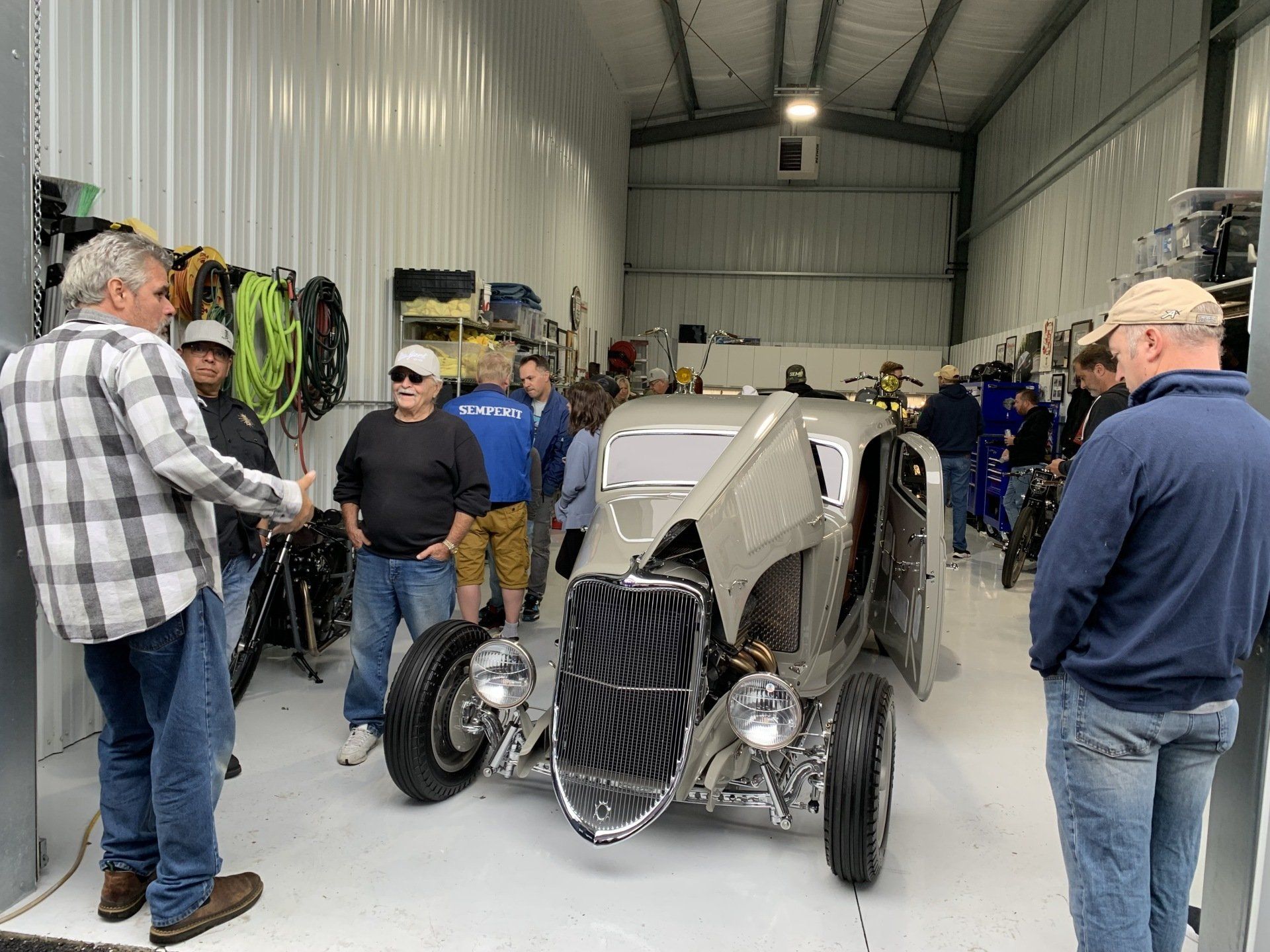 A group of men are standing around a car in a garage.