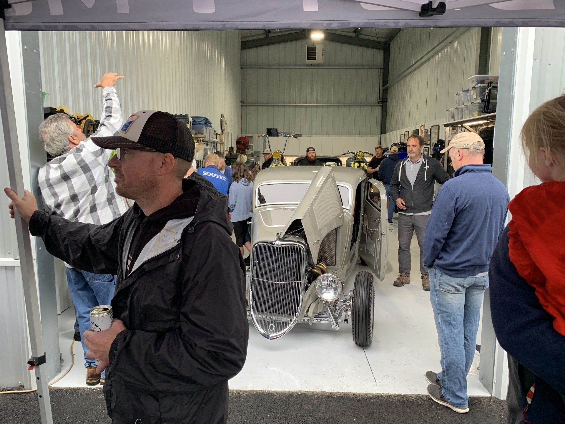 A group of people are standing around a car in a garage.