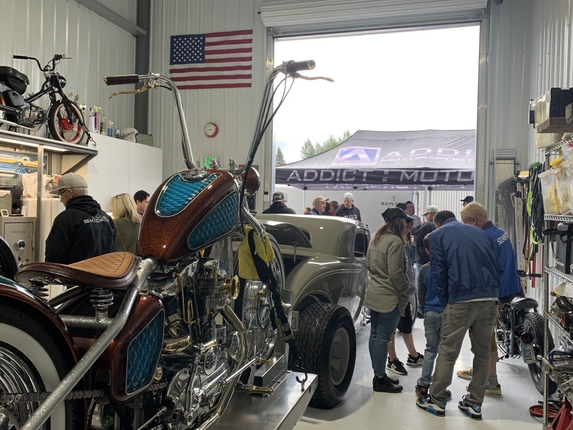 A group of people are standing around a motorcycle in a garage.