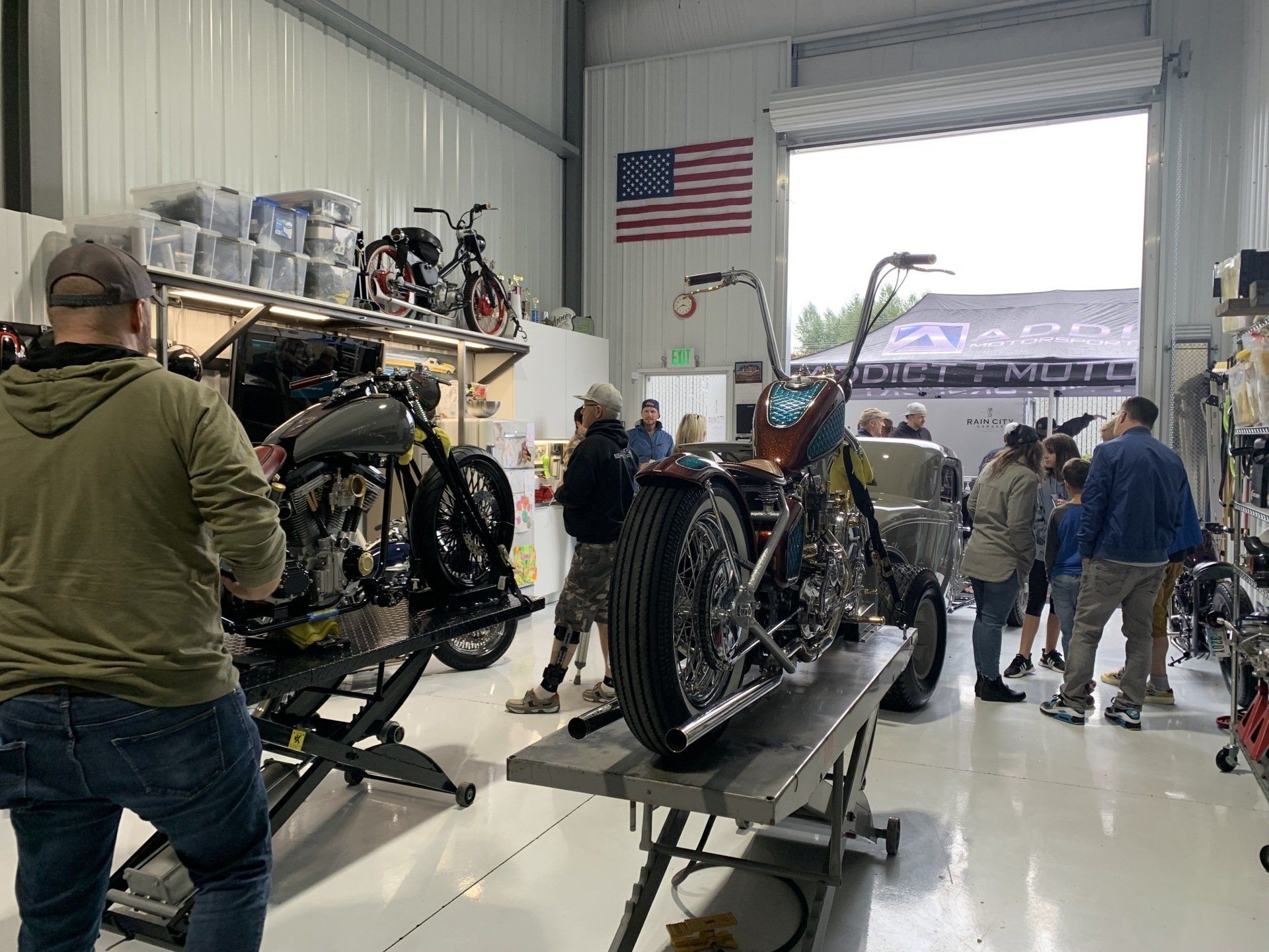 A group of people are standing around a motorcycle in a garage.