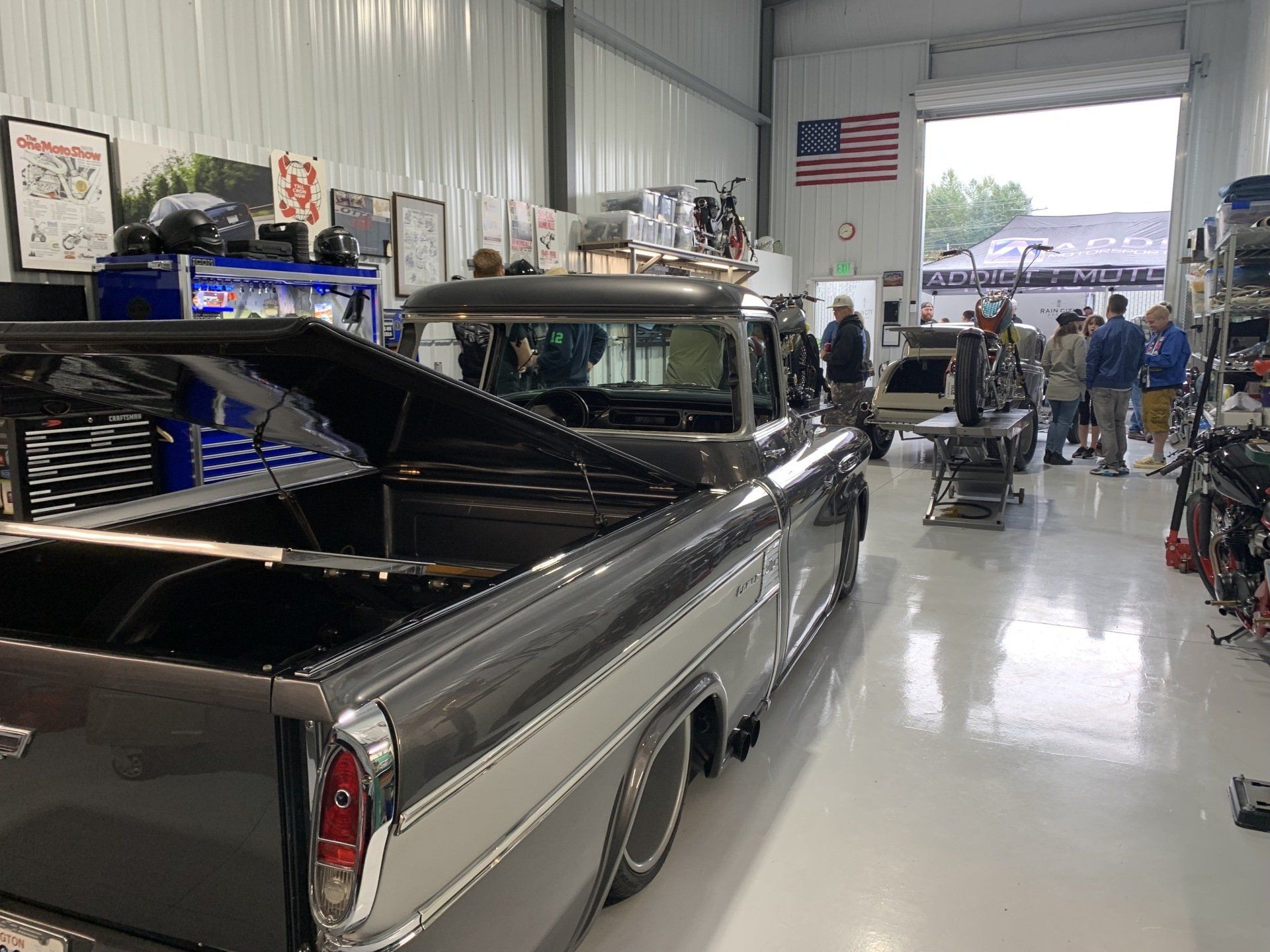 A truck is parked in a garage with a group of people standing around it.
