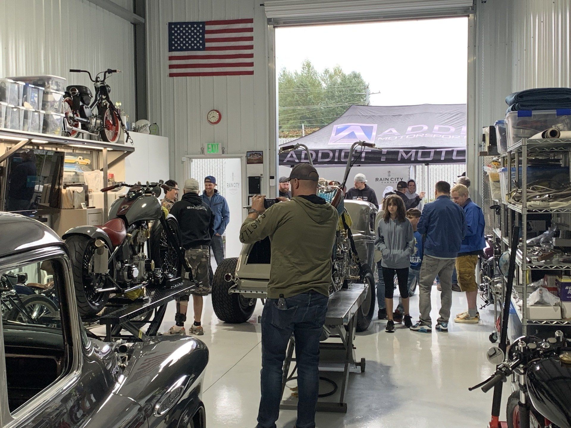 A man is taking a picture of a group of people in a garage.