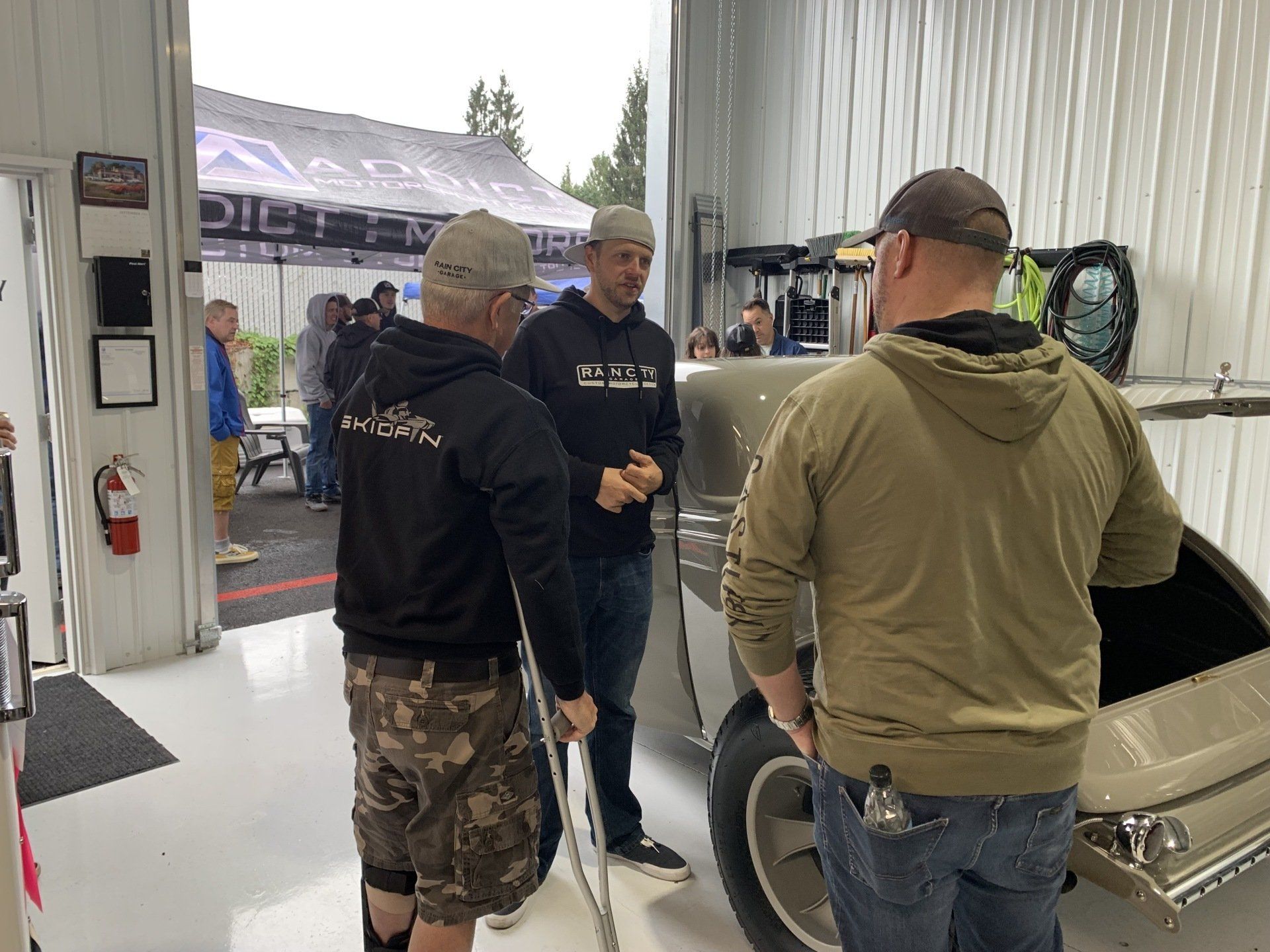 A group of men are standing around a car in a garage.
