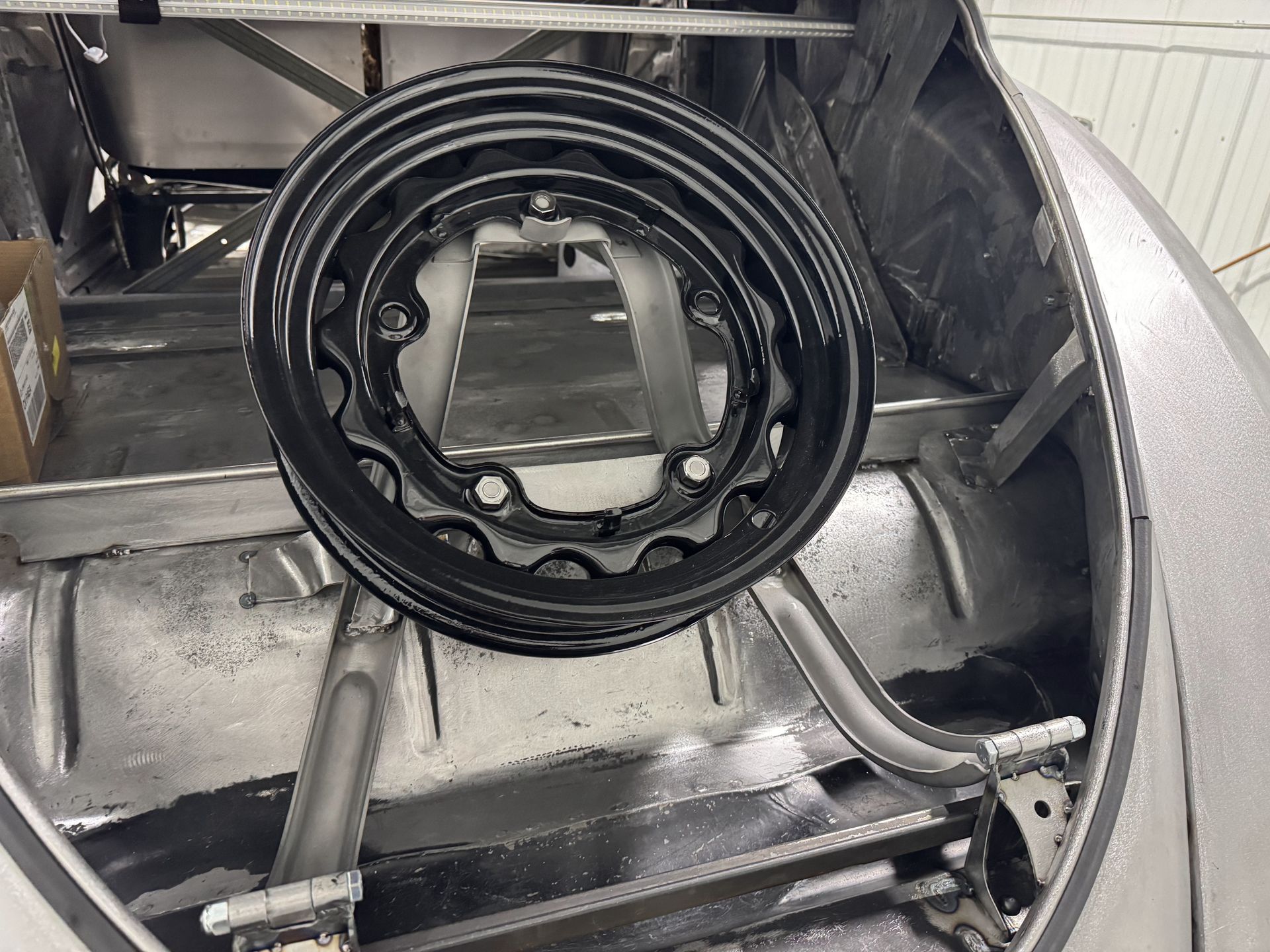 A black wheel is sitting in the trunk of a car