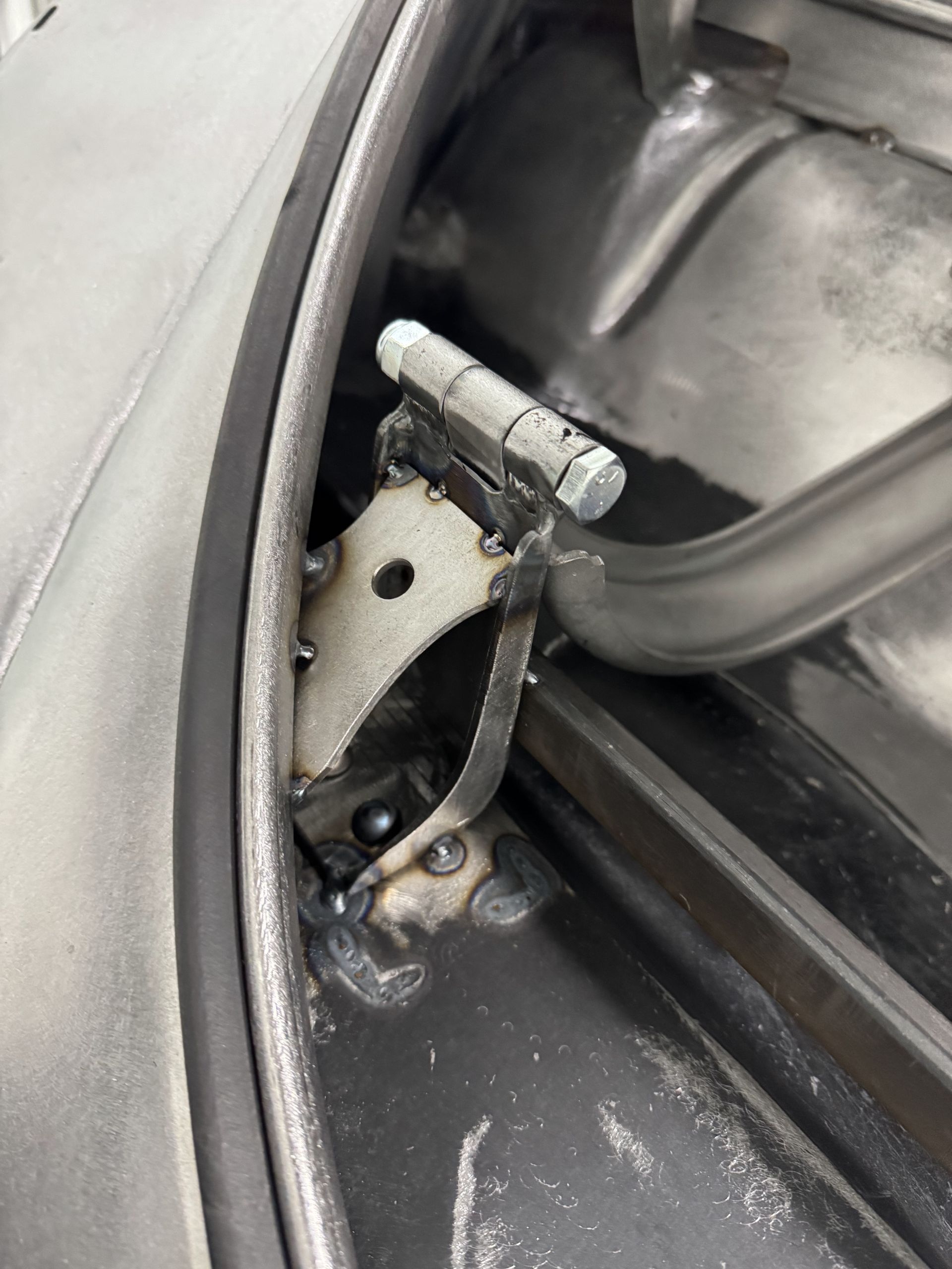 A close up of a door hinge on a car.