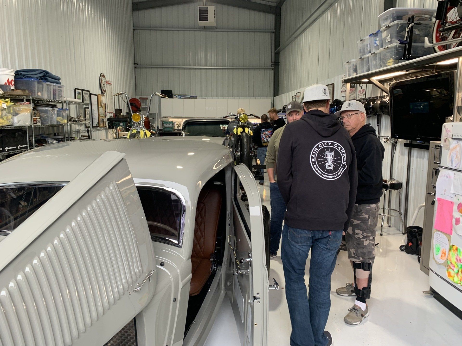 A group of men are standing around a car in a garage.