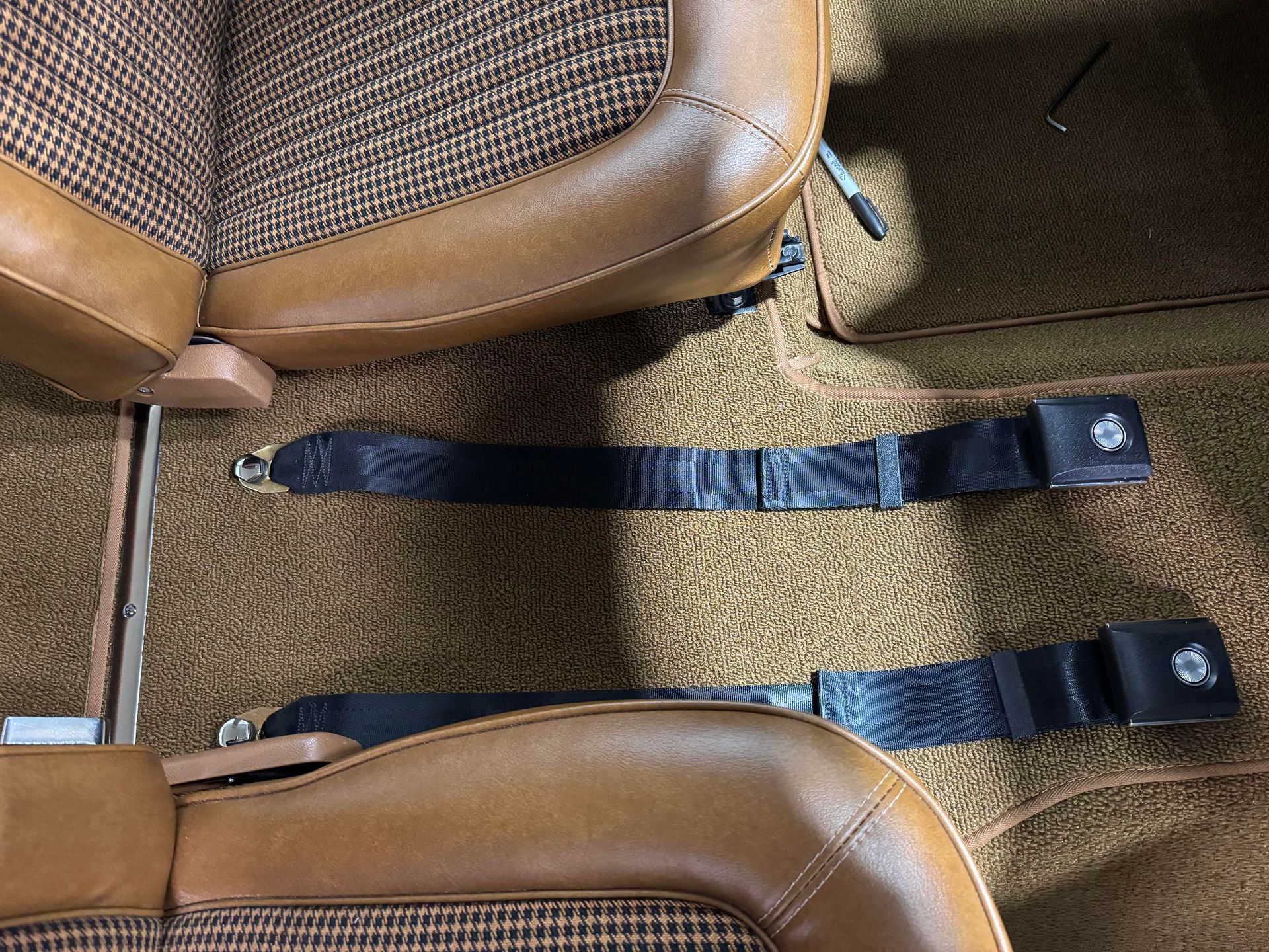 Two seat belts are attached to the back of a car seat.