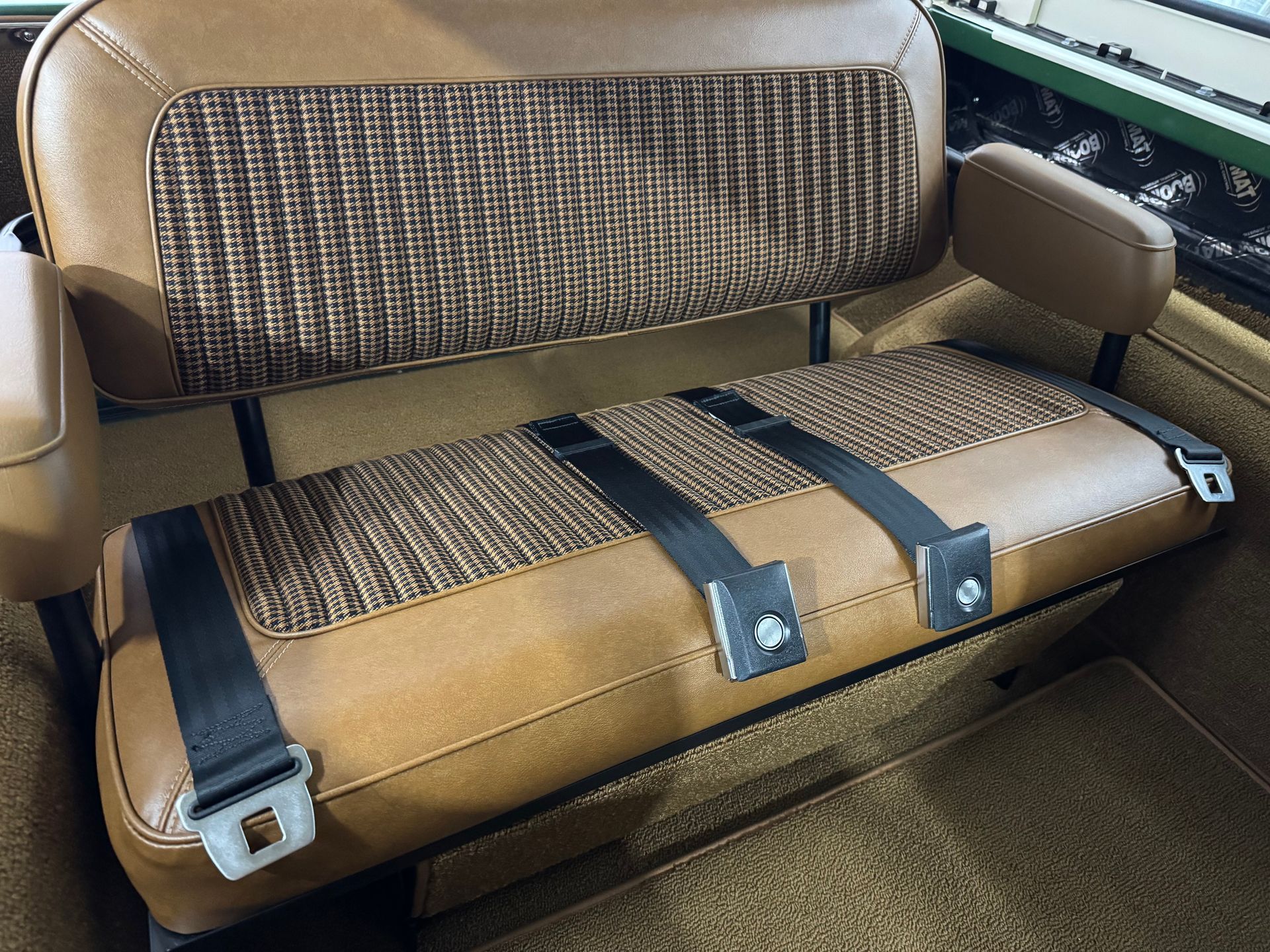 A brown car seat with black belts on it