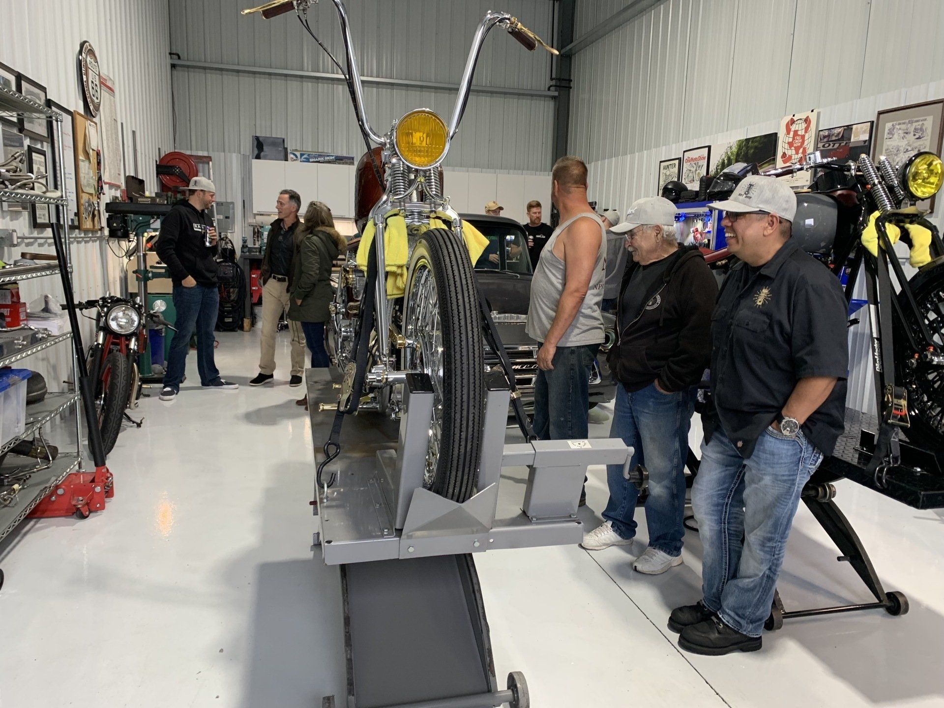 A group of men are standing around a motorcycle in a garage.