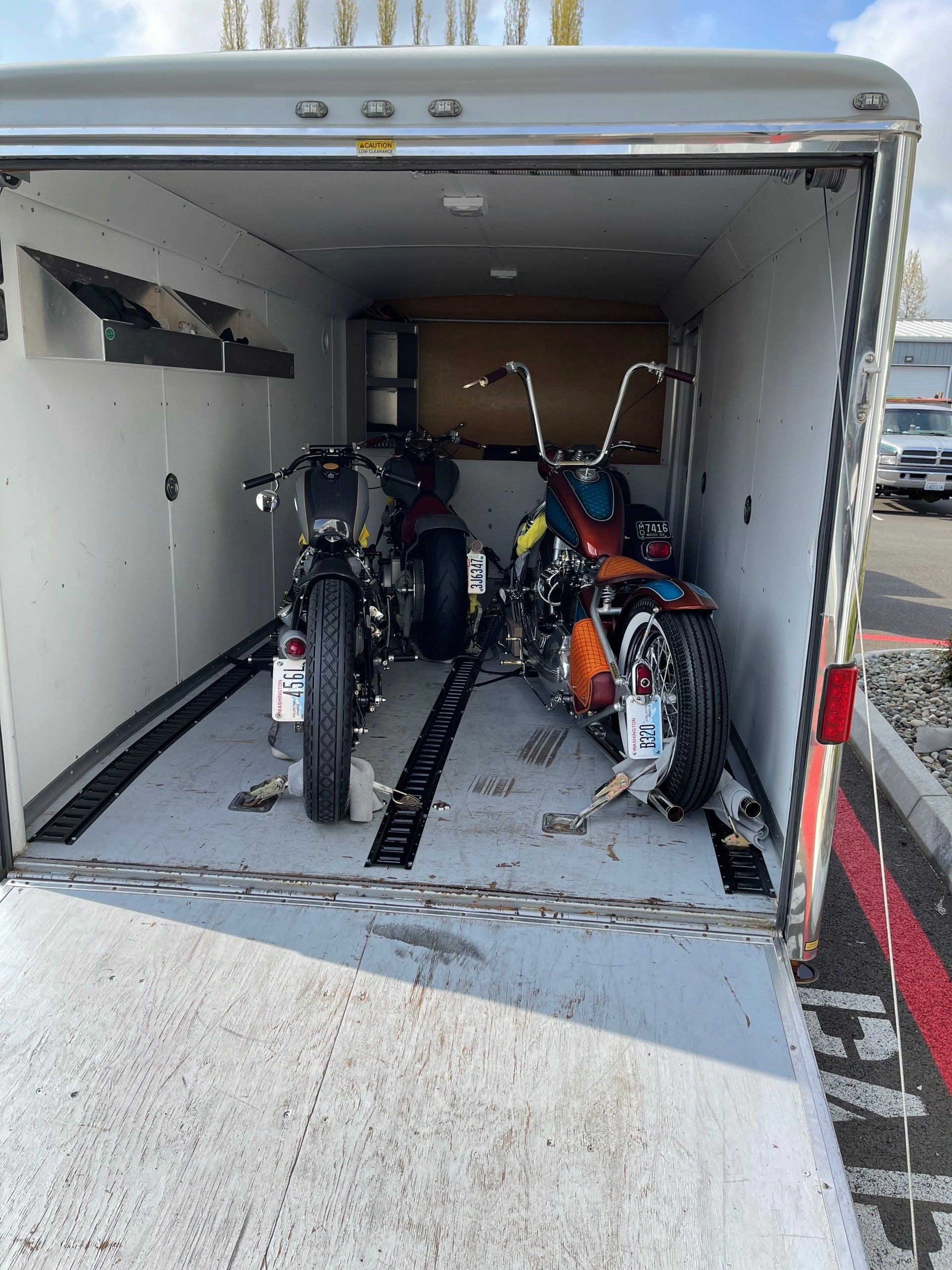 Two motorcycles are sitting inside of a trailer.