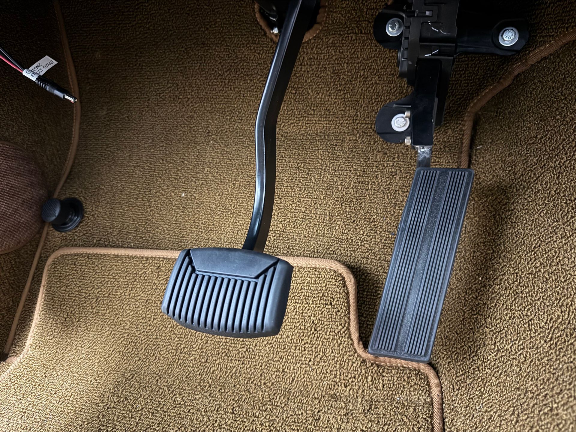 A close up of a car 's brake pedal on a carpeted floor.