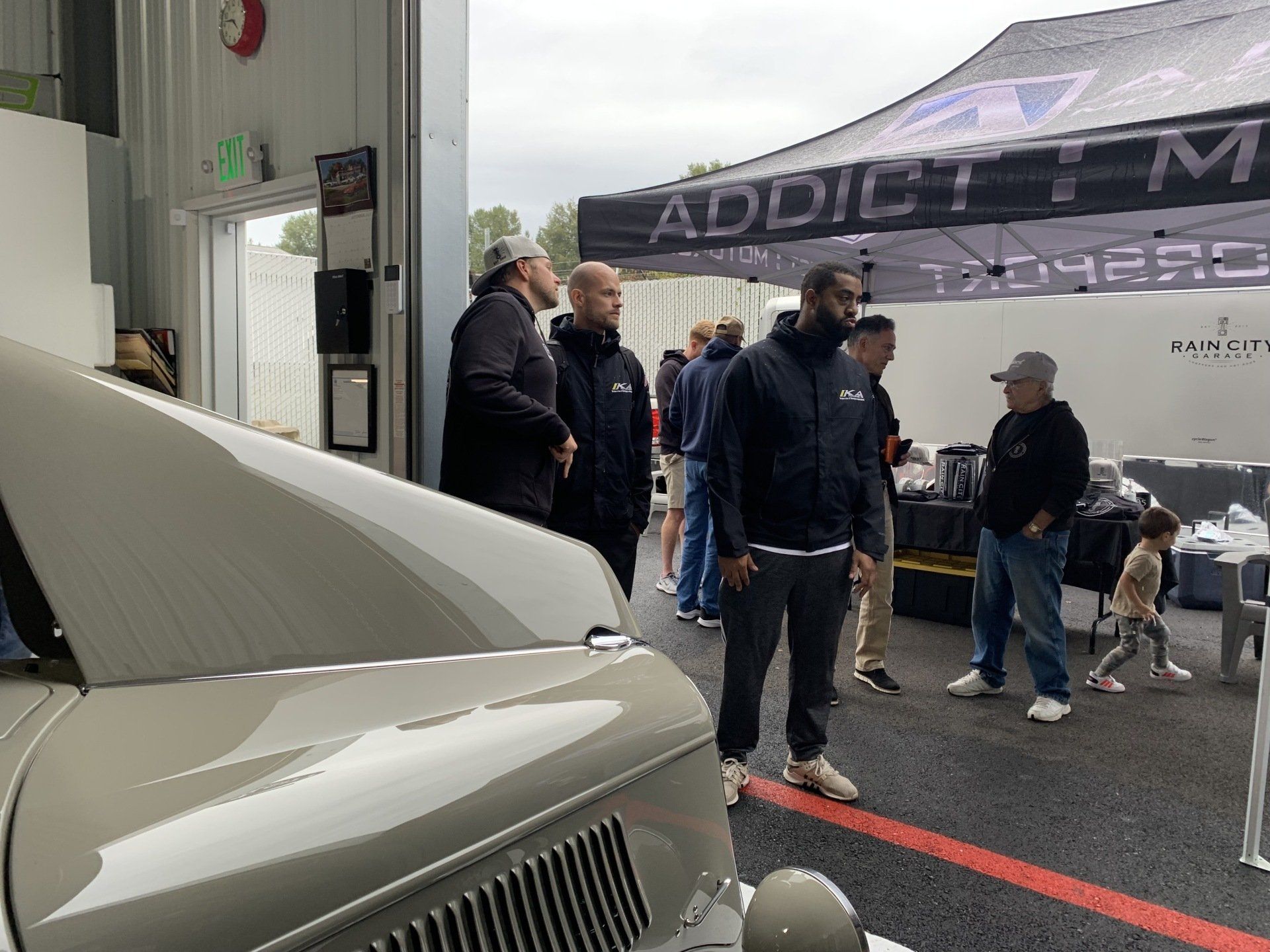 A group of men are standing in front of a tent with the word addict on it.