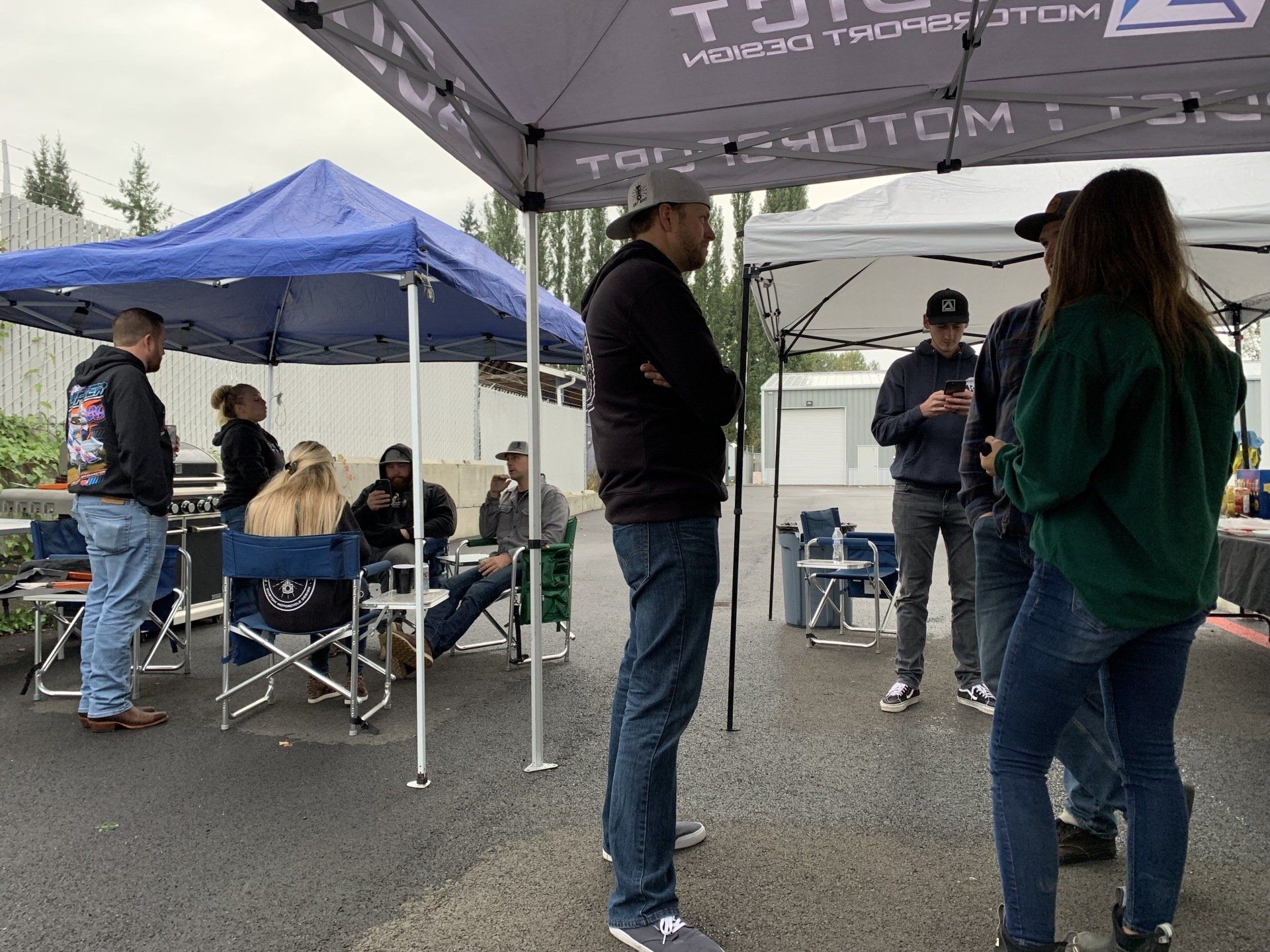 A group of people are standing under tents in a parking lot.