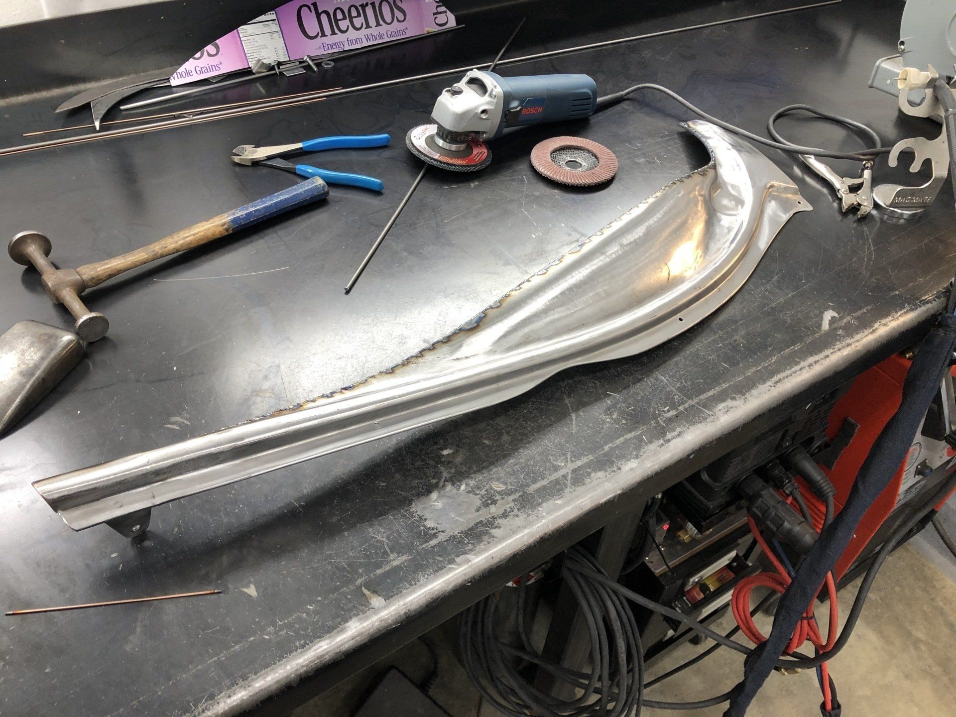 A hammer and a grinder are on a table next to a cheerios candy bar