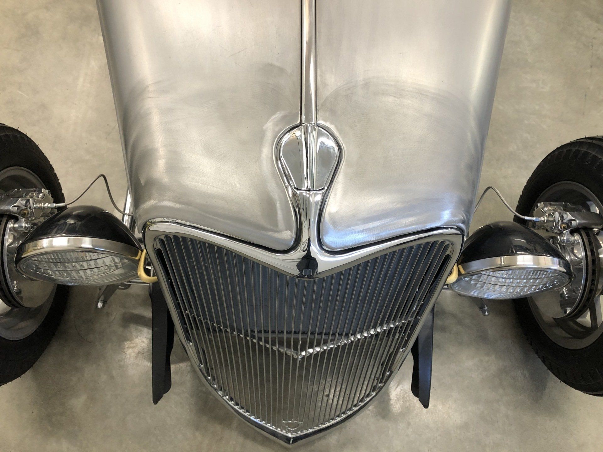 A close up of the front of a silver car with a chrome grill.