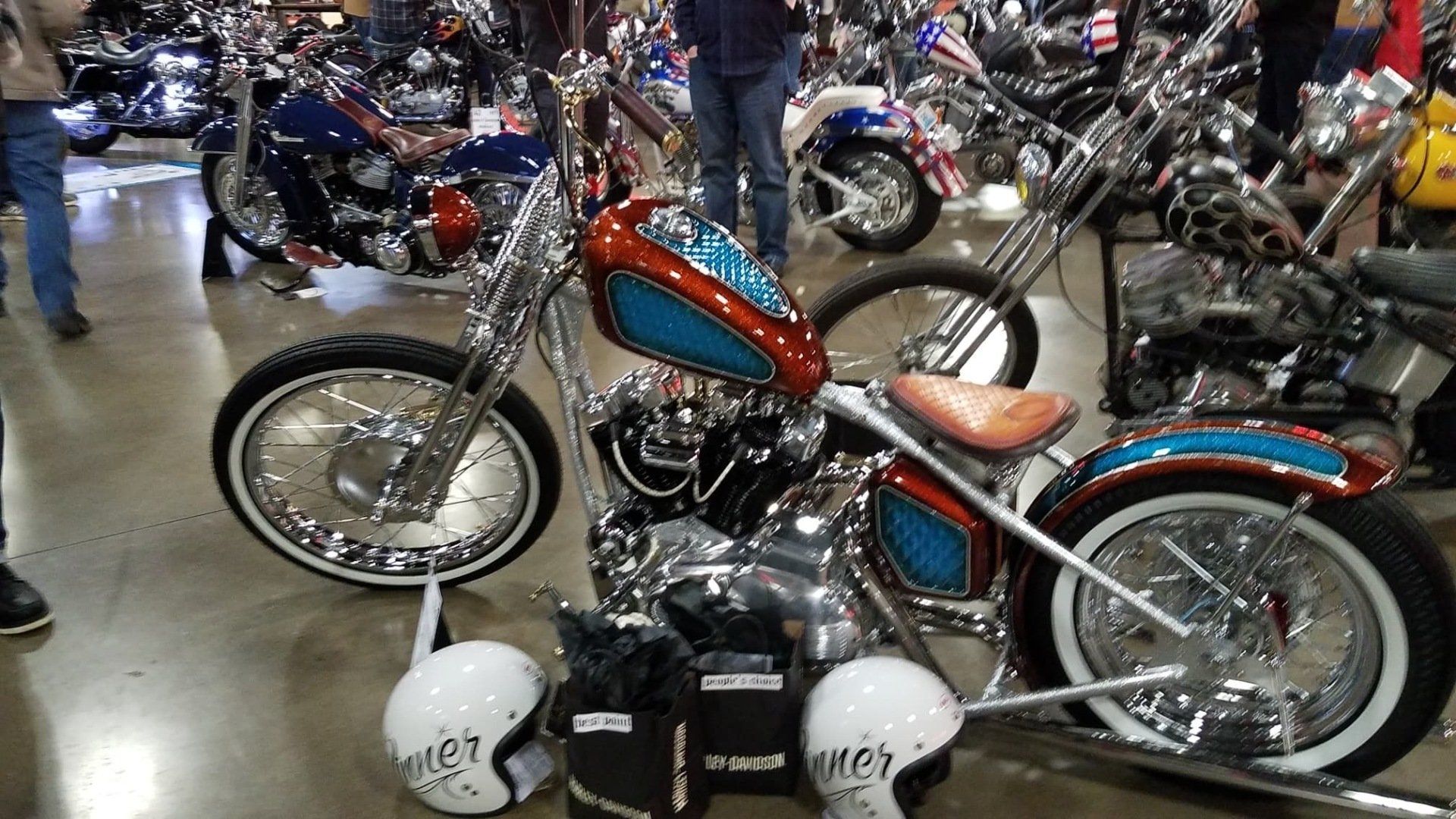 A red and blue motorcycle is parked next to two white helmets