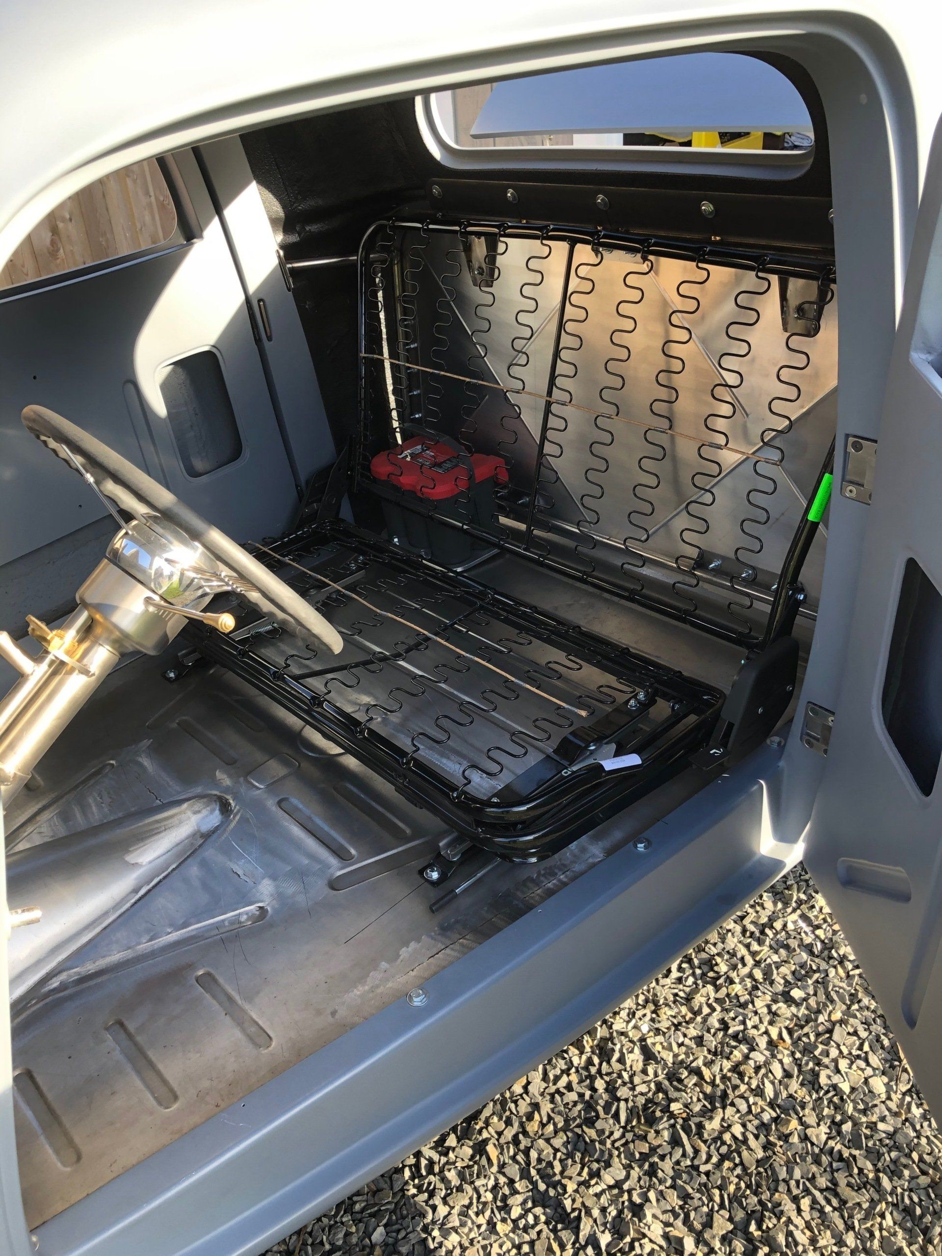 The inside of a car with the door open and a steering wheel.