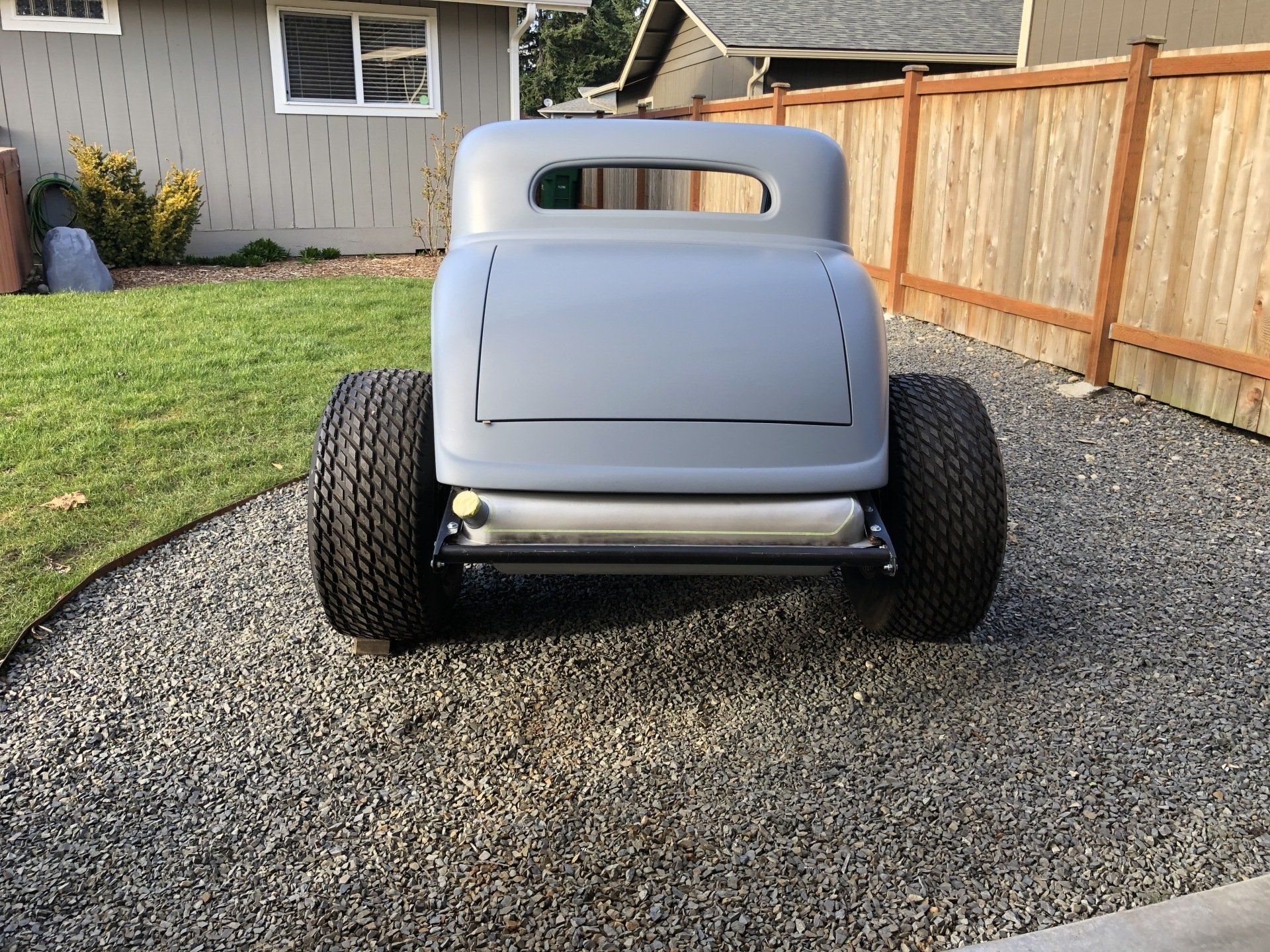 A car is parked on gravel in front of a house