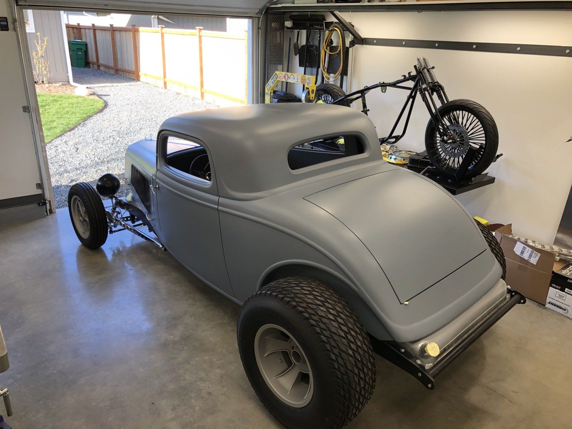 A car is parked in a garage next to a motorcycle.