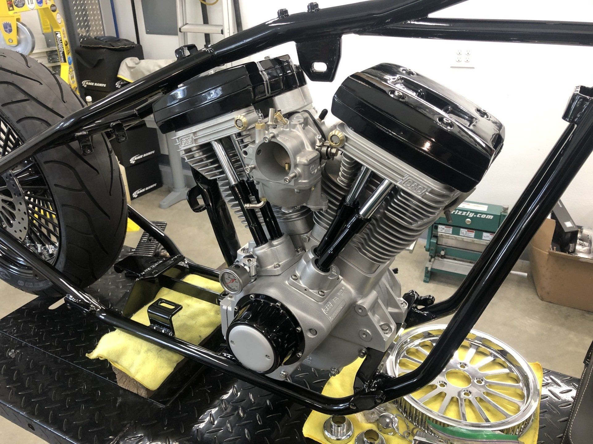 A motorcycle engine is sitting on top of a table in a garage.